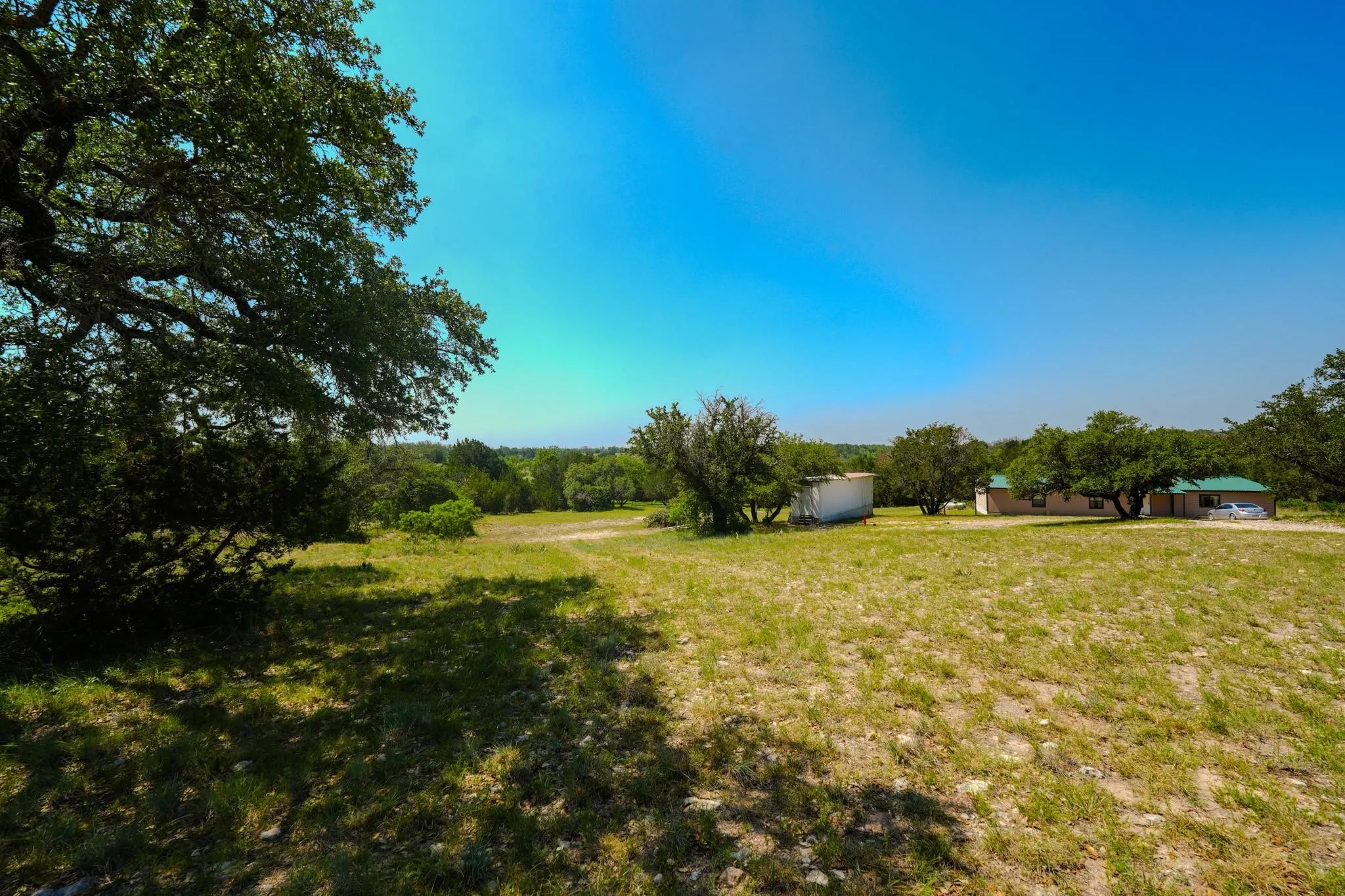 Expansive grounds featuring mature trees and a residential structure with a green metal roof