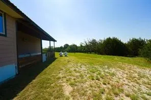 Expansive exterior grounds featuring a covered porch, horizontal siding, and mature perimeter trees