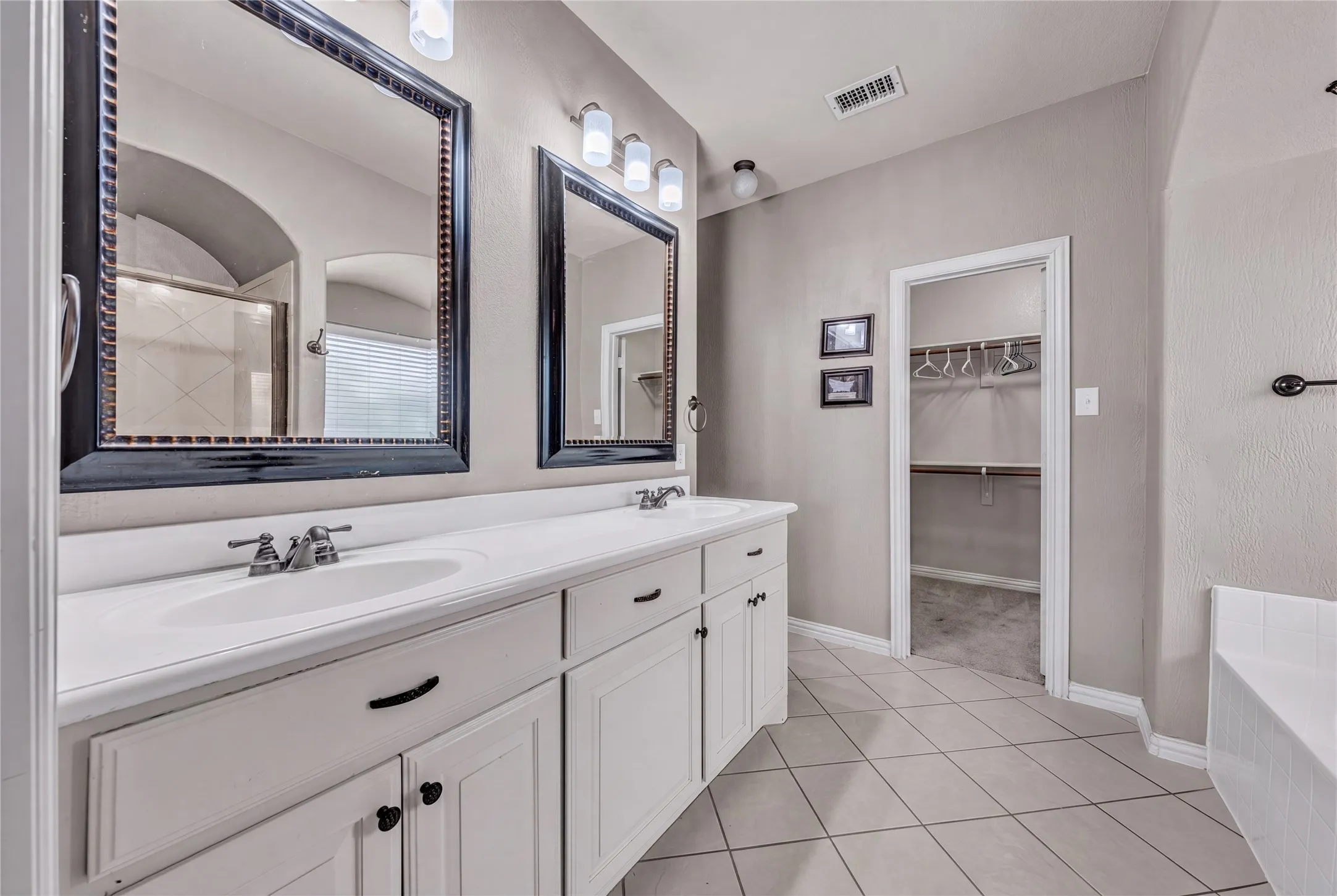 Dual vanity with white cabinetry and integrated sinks, complemented by framed mirrors and sconce lighting