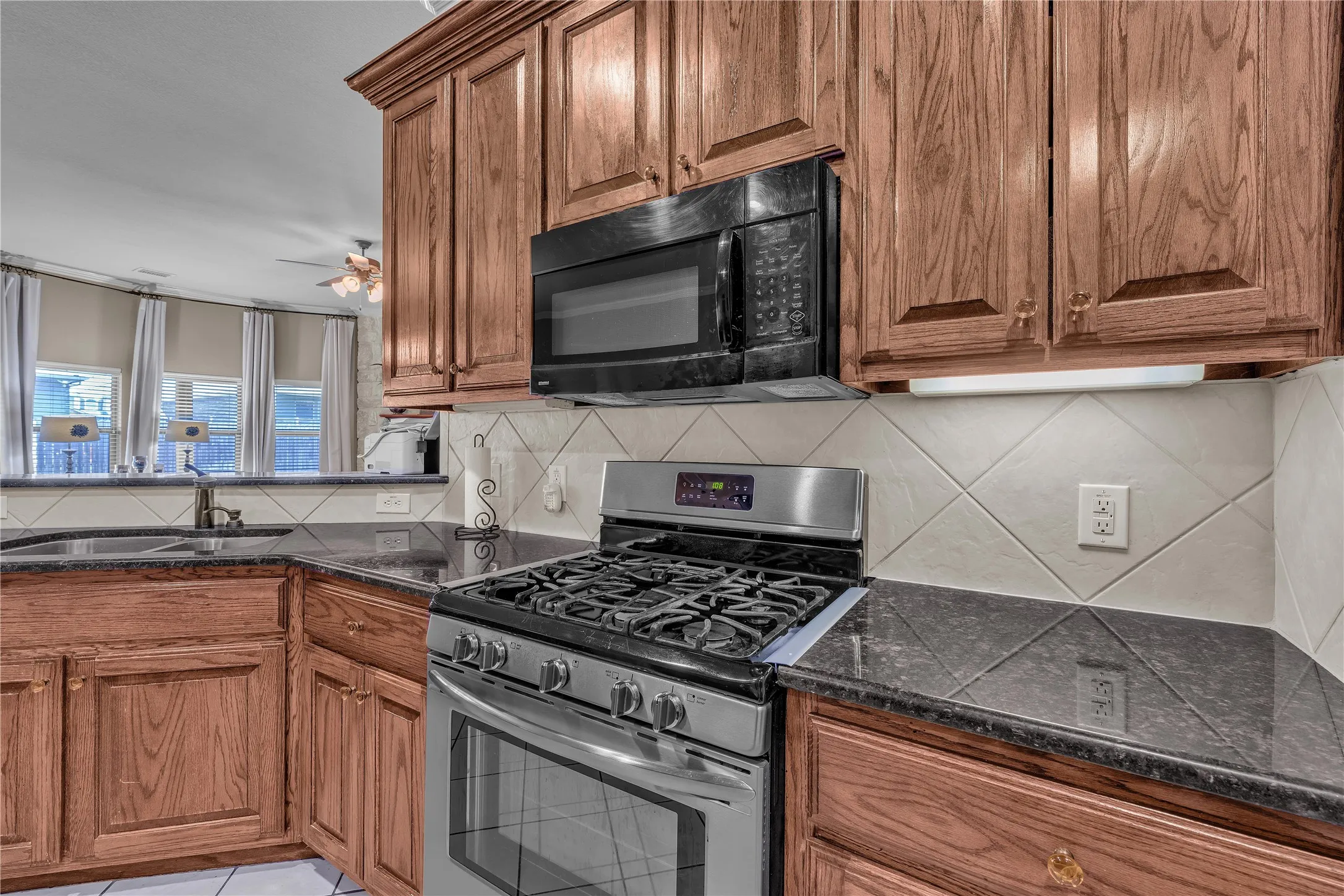 Kitchen featuring wood cabinetry, dark countertops, a stainless steel range, and an over-the-range microwave