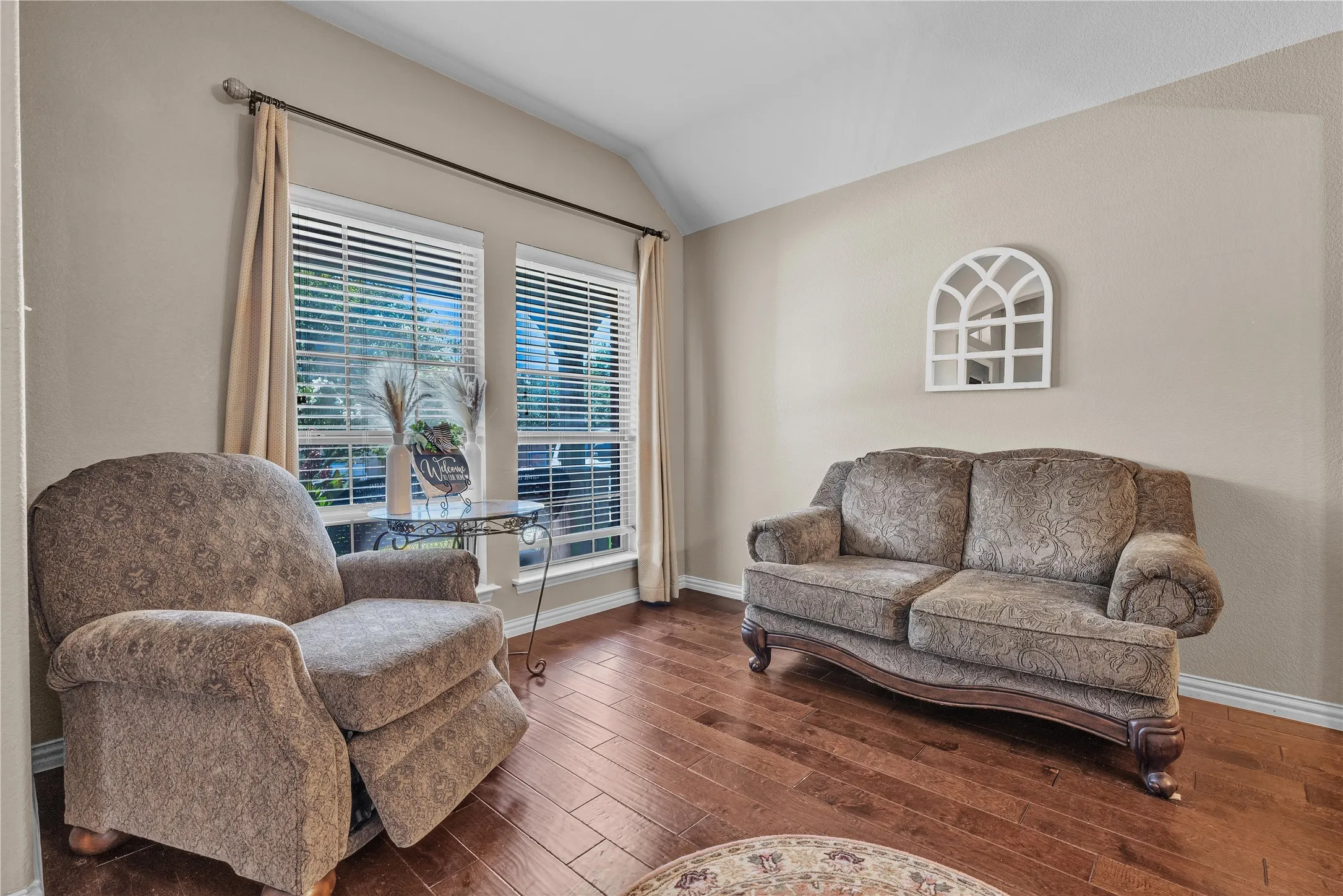 Spacious room featuring vaulted ceilings, wood-finish flooring, and neutral wall tones