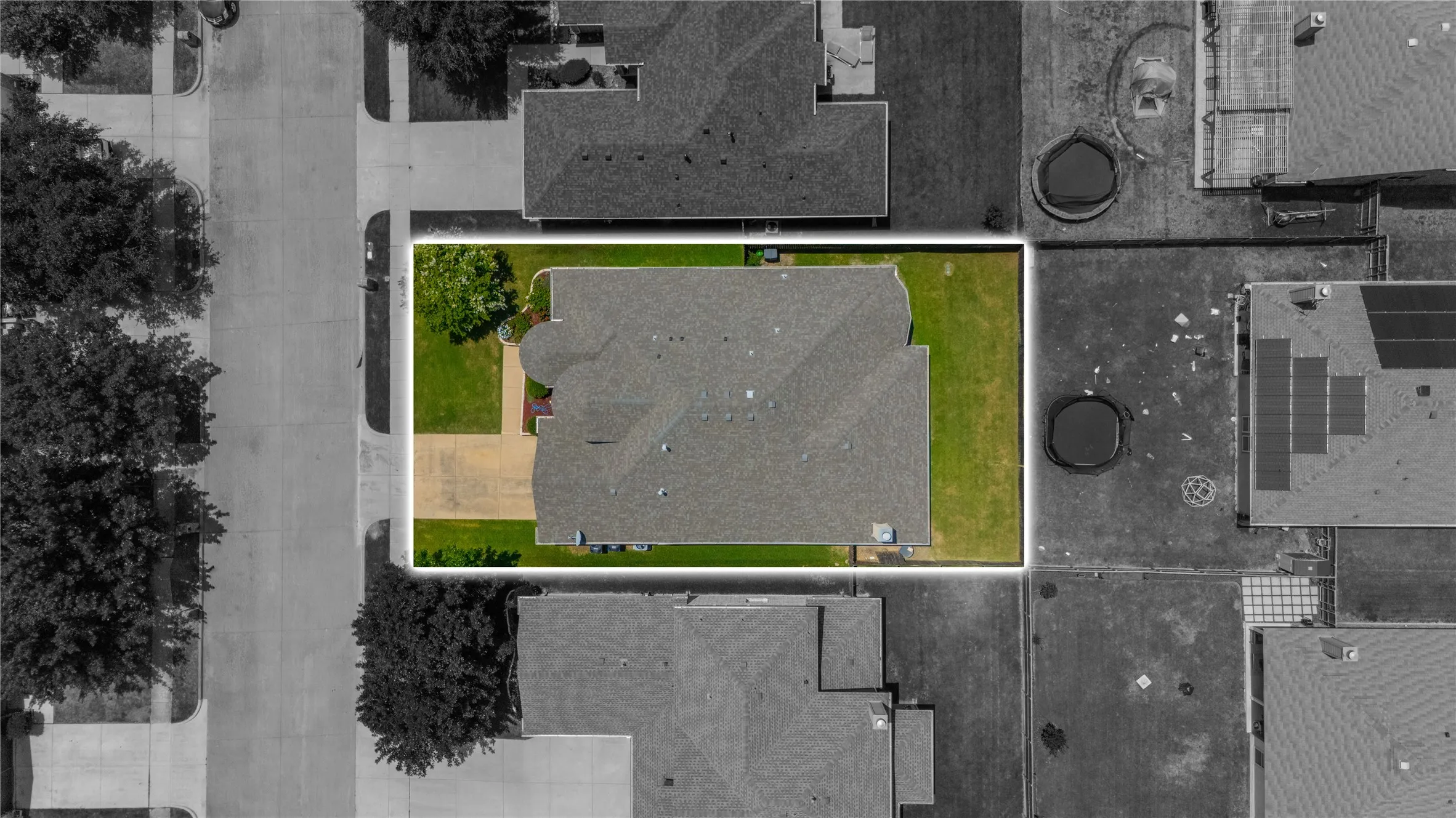 Aerial view showcasing a residential property with a gray shingle roof and a spacious green lawn