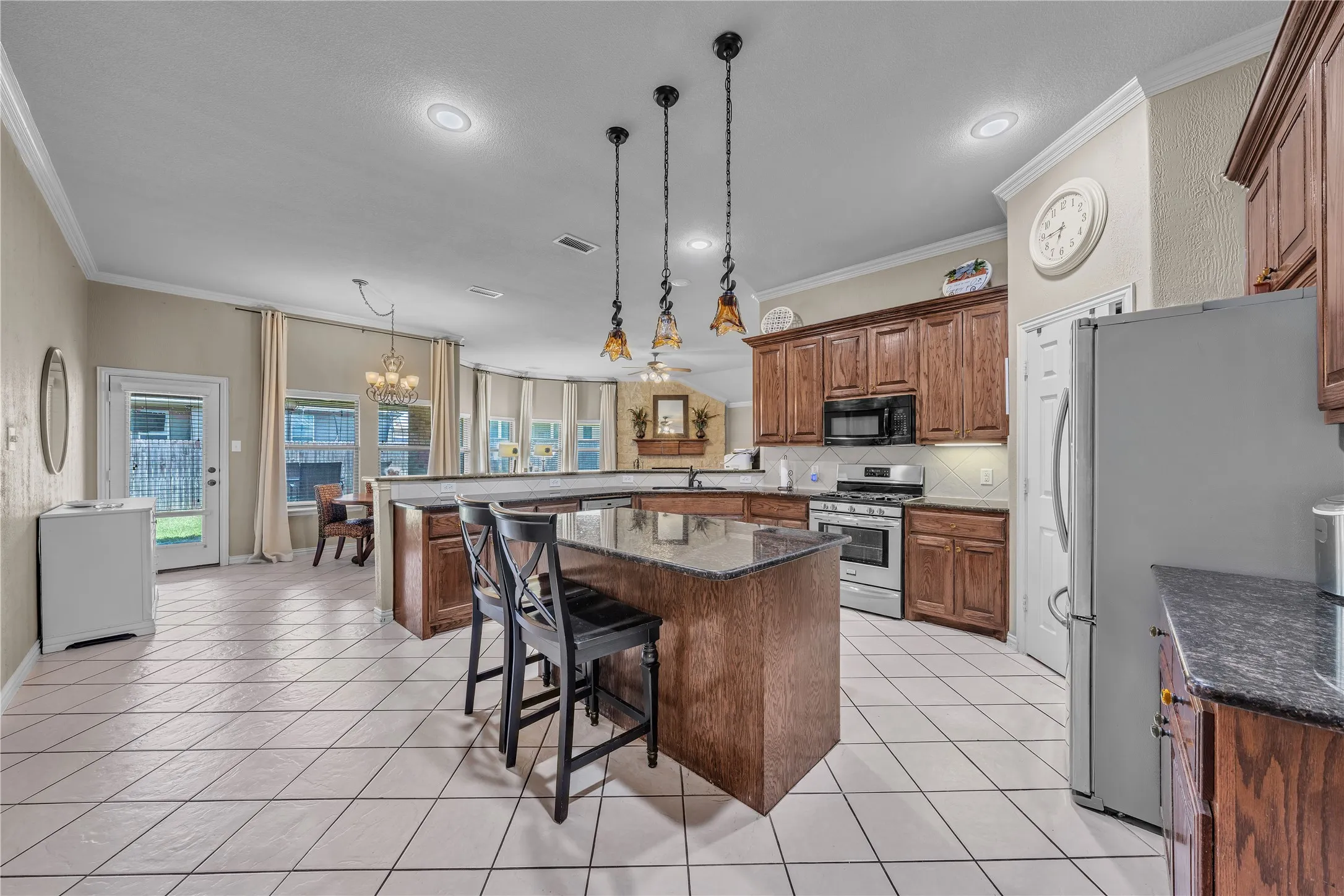 Spacious kitchen featuring a central island with bar seating, overhead pendant lighting, and granite countertops