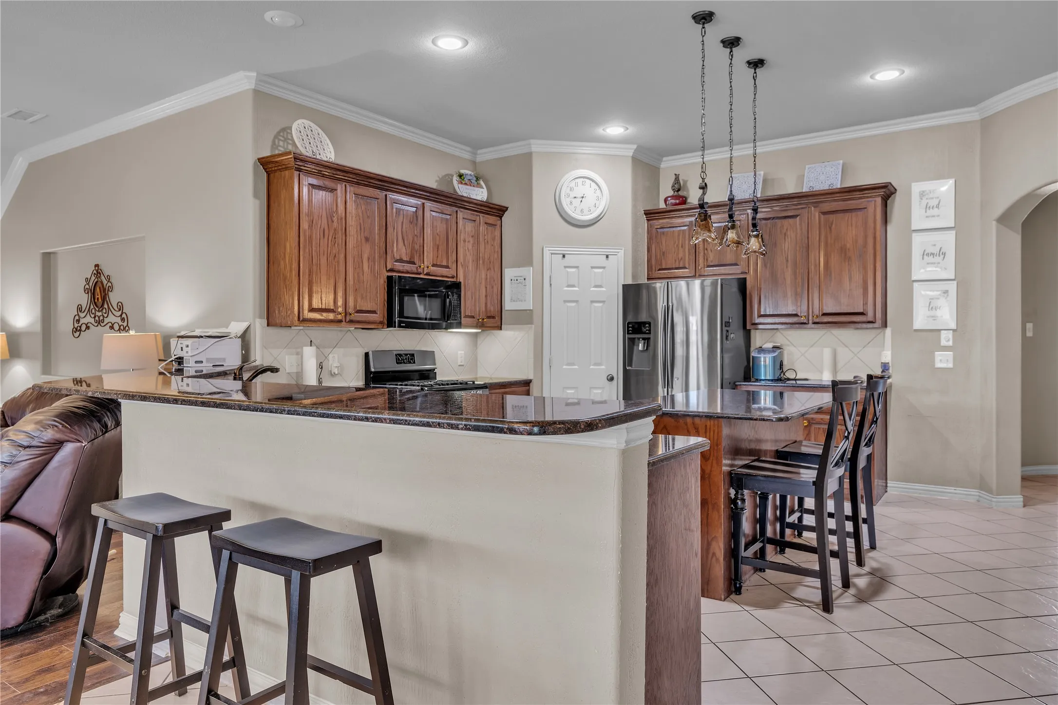 Kitchen featuring dark wood cabinetry, stainless steel appliances, and a breakfast bar with stone-finish countertops