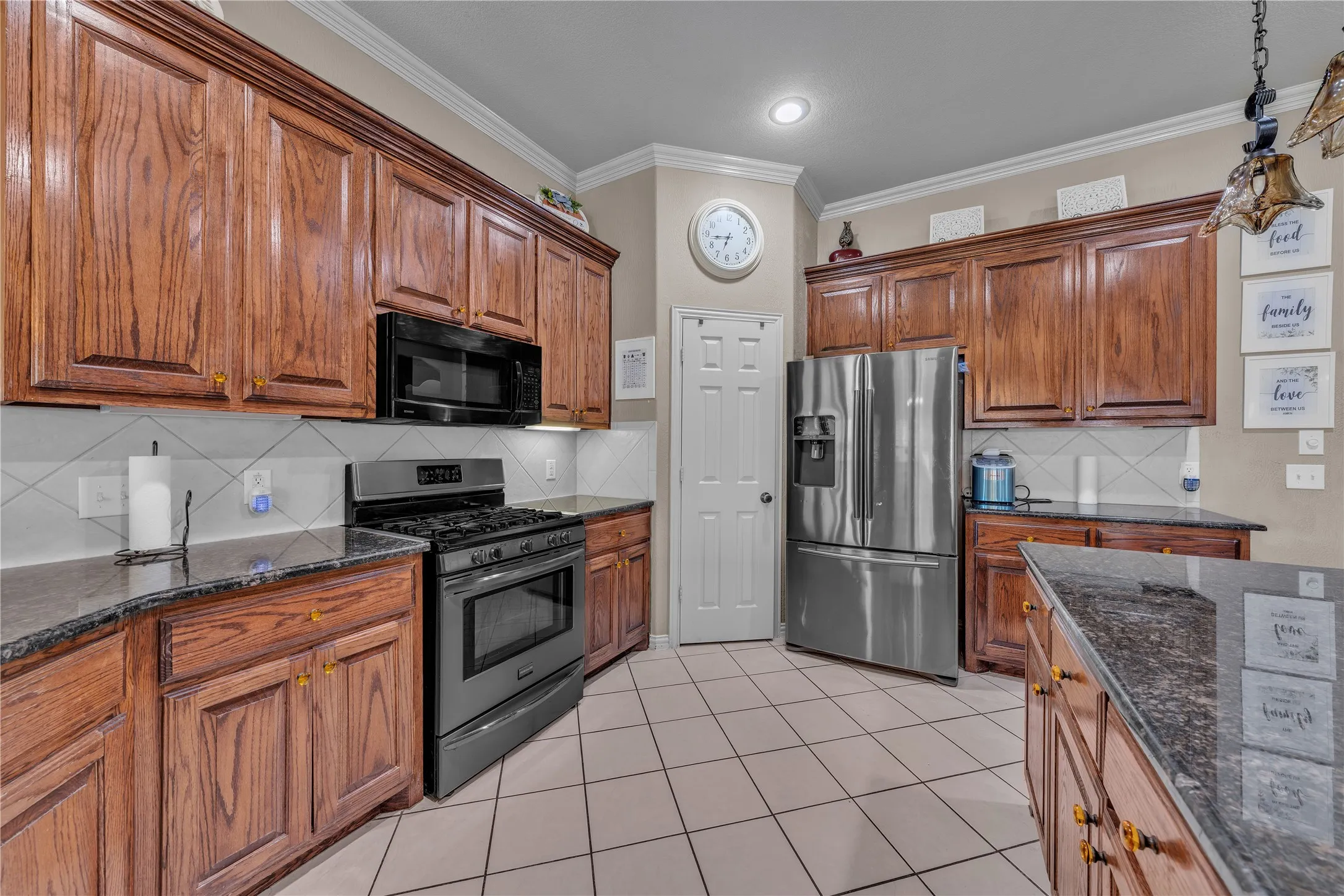 Kitchen featuring wood cabinetry, stainless steel appliances, dark stone countertops, a tile backsplash, and tile flooring