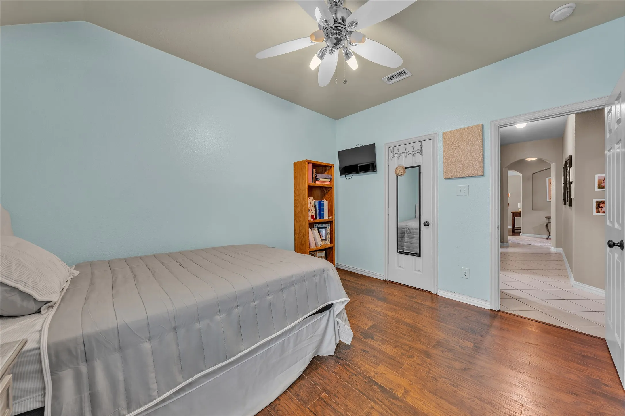 Room featuring wood-finish flooring, light blue walls, and a ceiling fan with integrated lighting