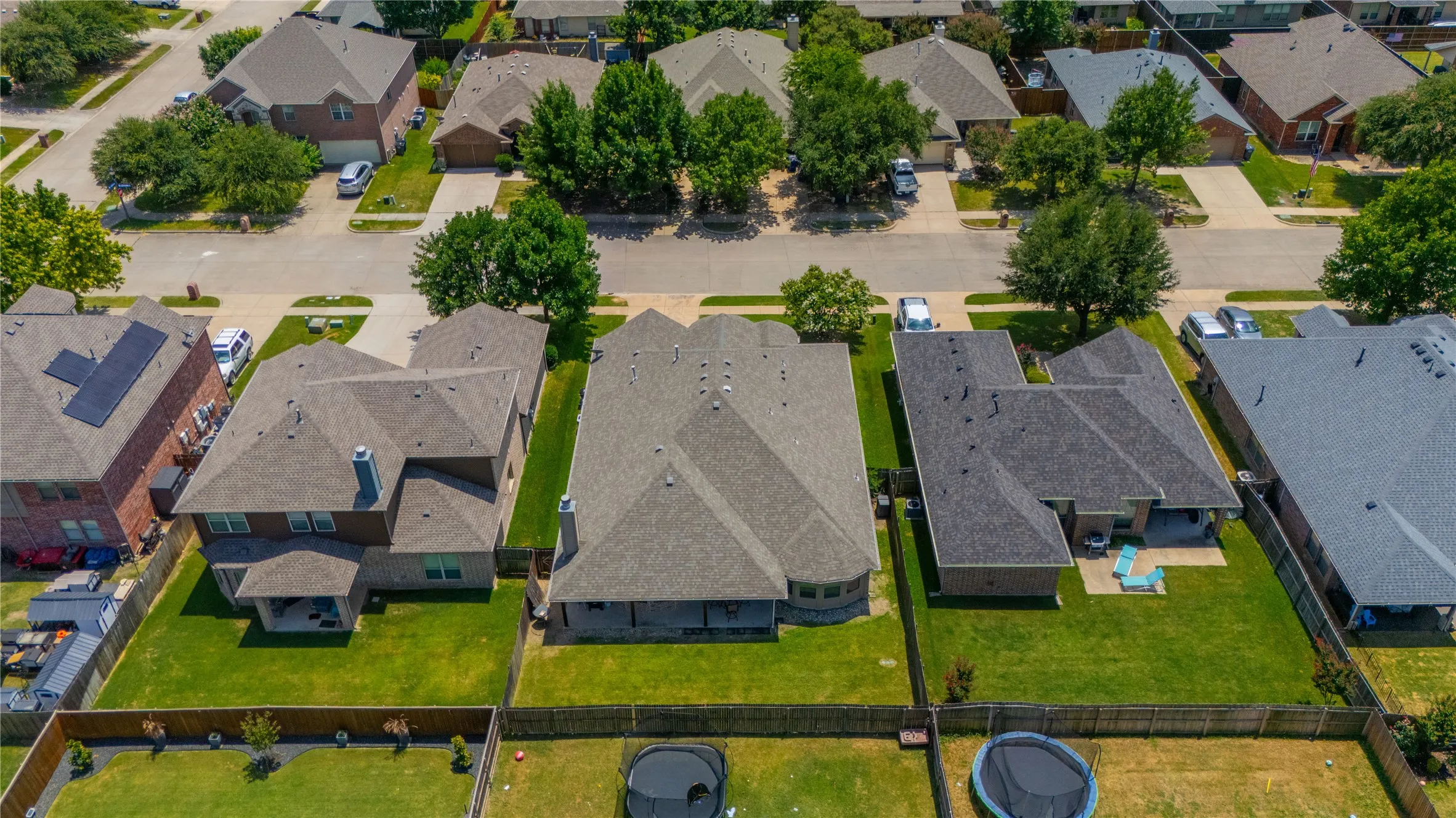 Spacious residential property featuring a large backyard with a covered patio, a manicured lawn, and a perimeter fence