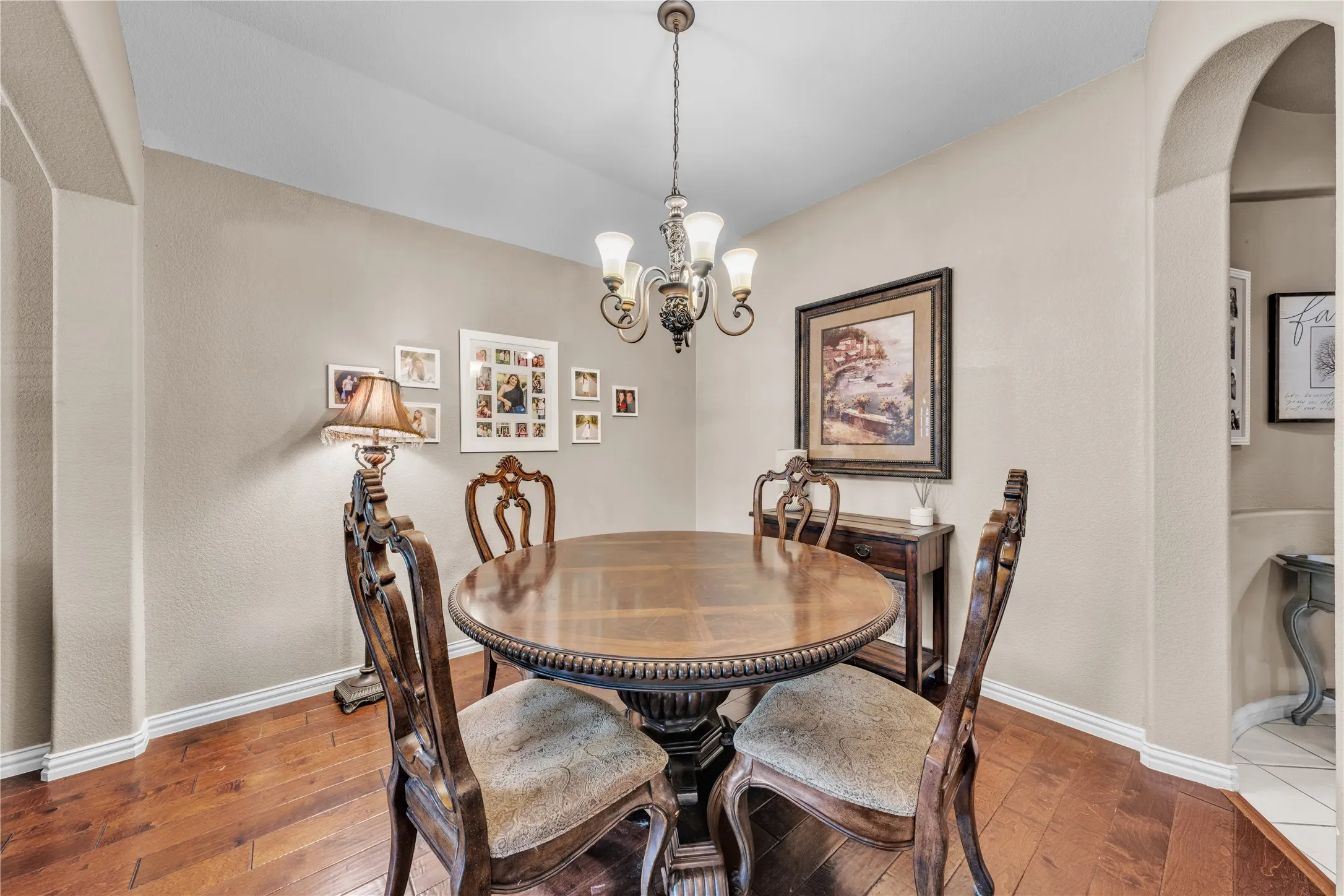 Dining area featuring wood-finish flooring, an arched doorway, and a chandelier with glass shades