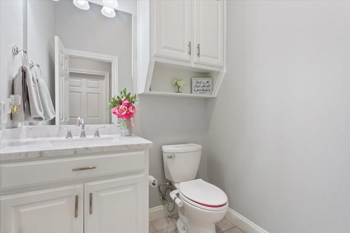 Bathroom featuring a white vanity with a light-colored countertop, a chrome faucet, a large wall mirror, and overhead lighting