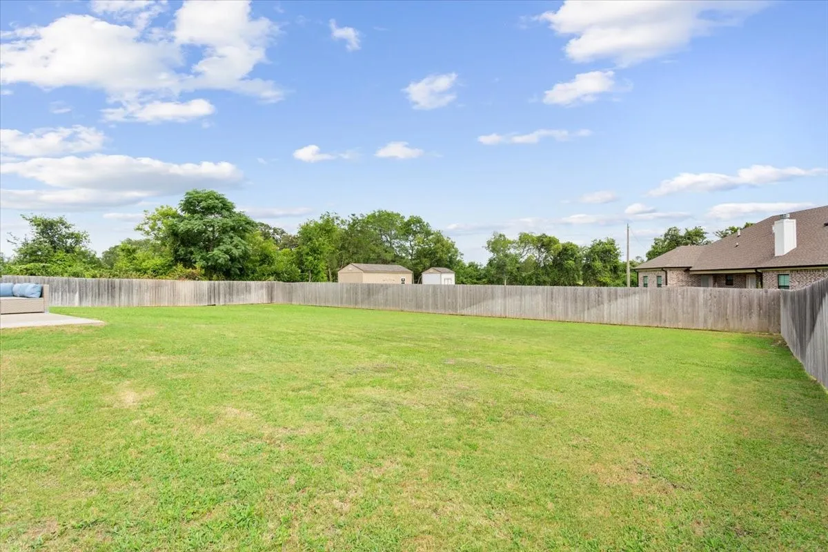 Expansive backyard featuring a manicured lawn, a concrete patio area, and a privacy fence enclosing the perimeter