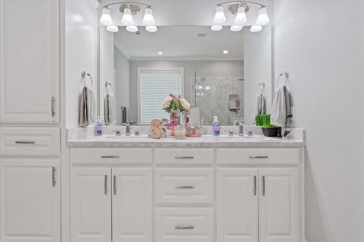 Dual vanity with undermount sinks, stone countertop, brushed nickel fixtures, and integrated storage cabinetry