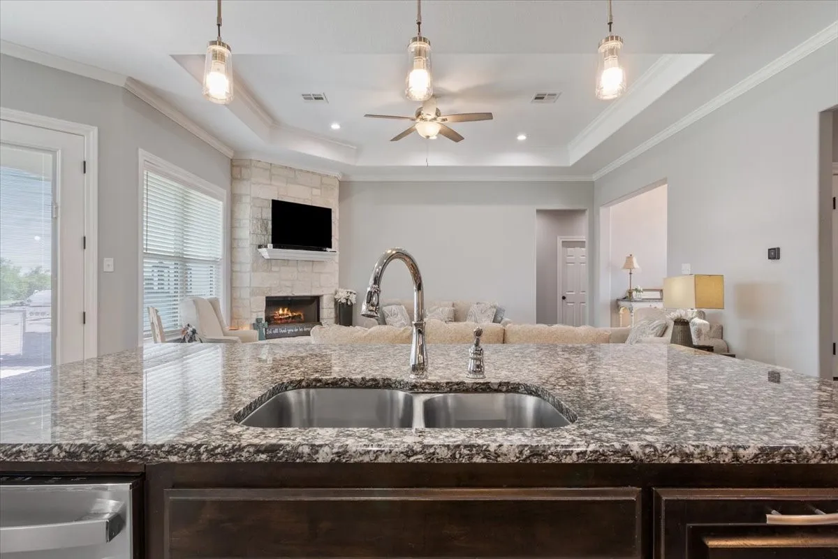 Kitchen island featuring a granite countertop with an undermount double basin sink and gooseneck faucet