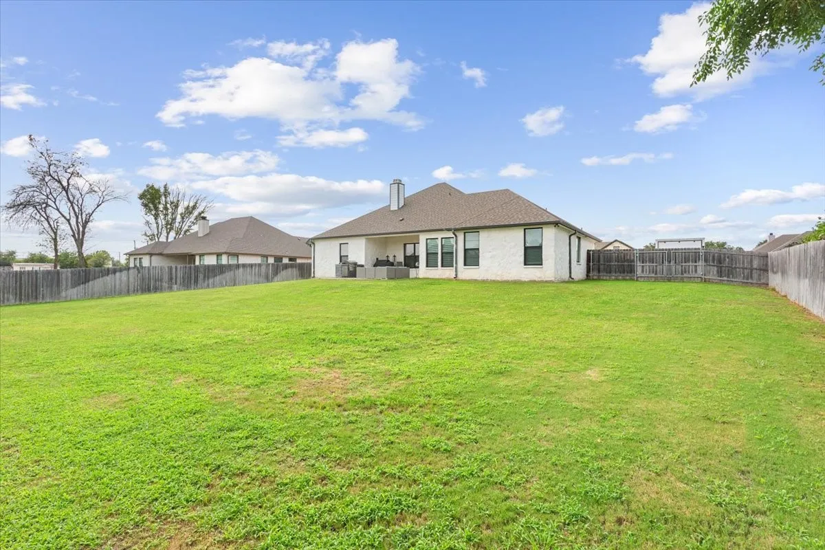Expansive green space featuring a large backyard and a partial wooden privacy fence