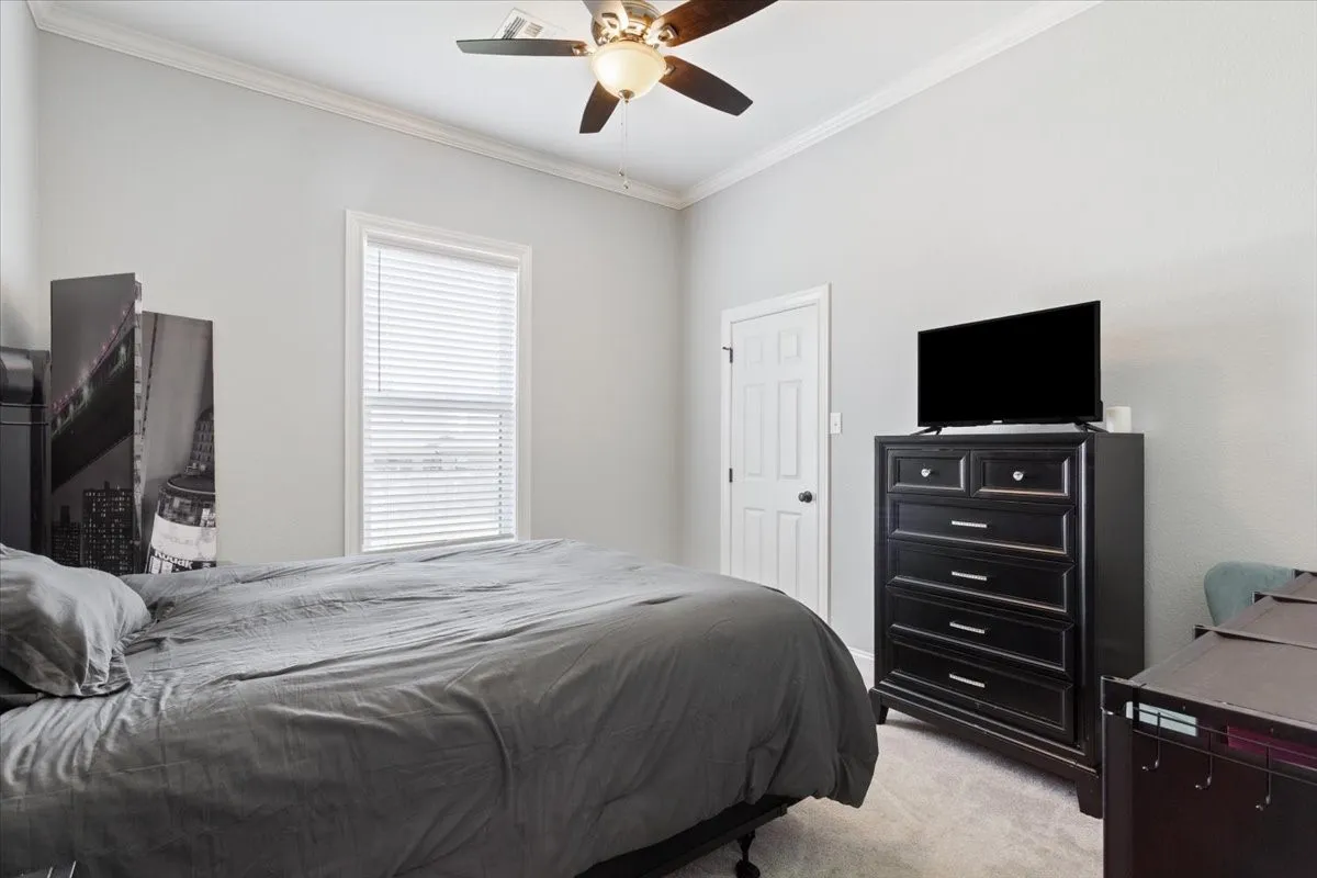 Room featuring light gray walls, white crown molding, and a ceiling fan with integrated lighting