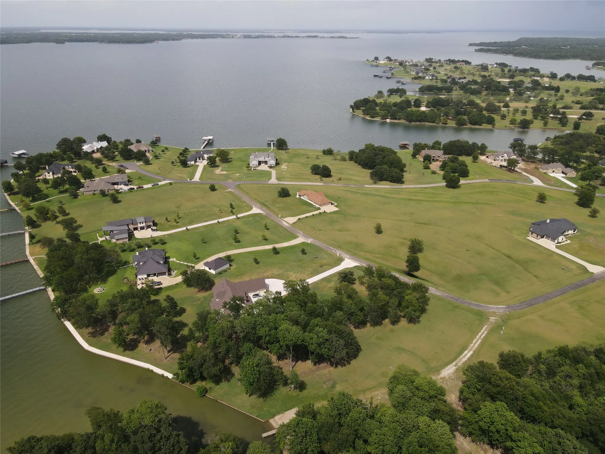 Expansive lakefront property featuring multiple residences, private docks, mature trees, and manicured lawns