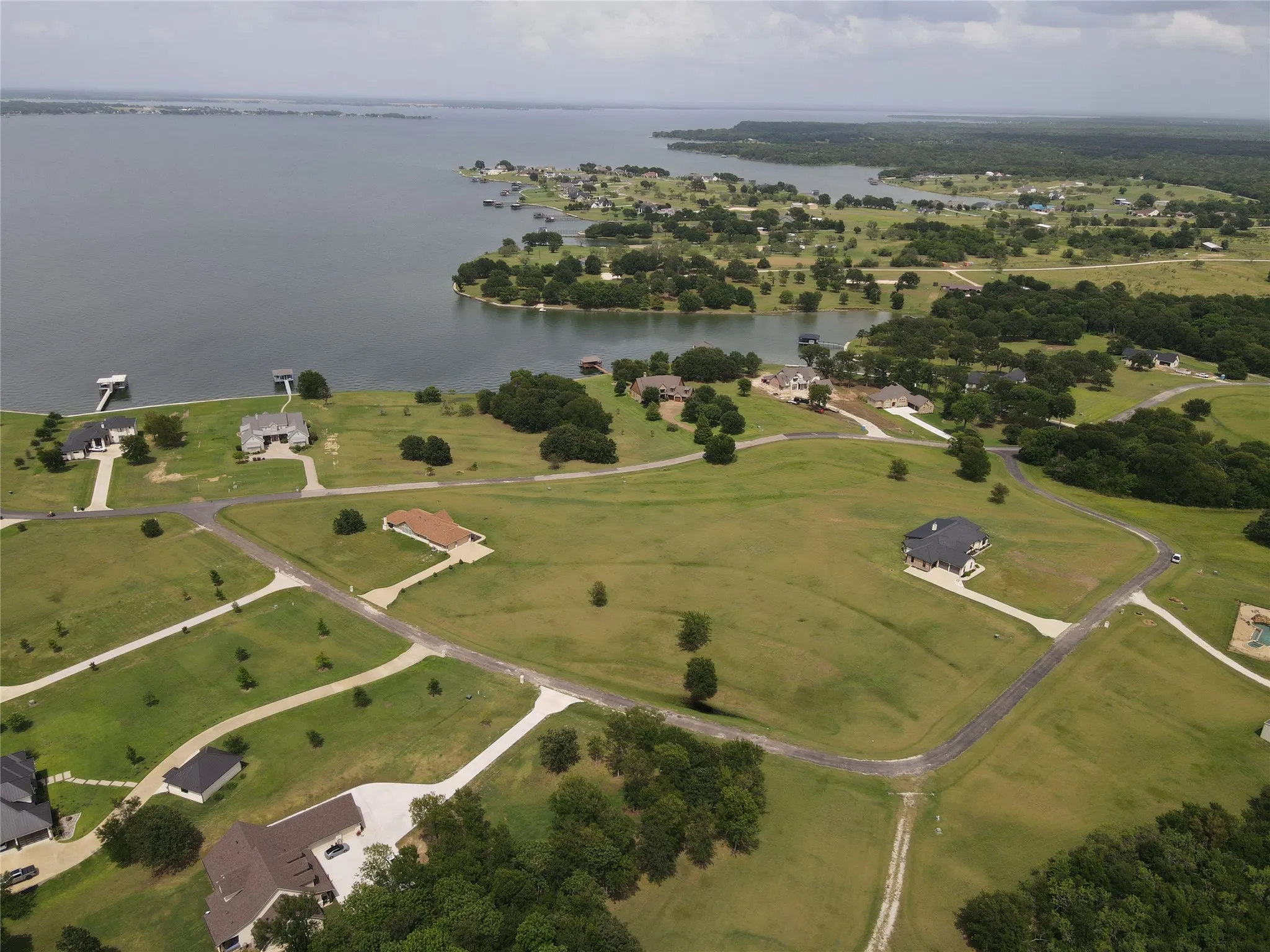 Expansive waterfront community featuring multiple residences, mature trees, and large green spaces