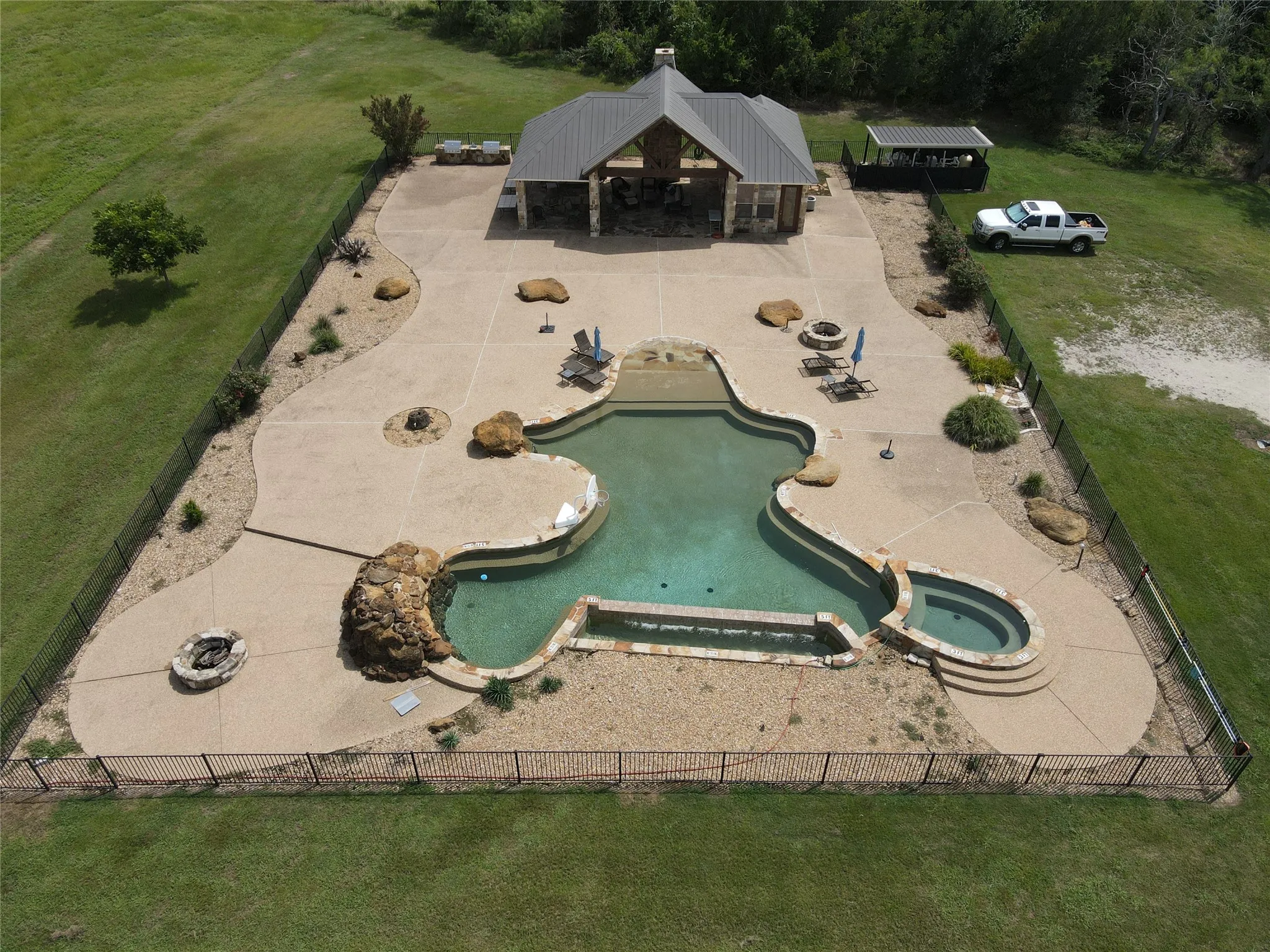 Curved concrete patio surrounding a freeform swimming pool with an integrated spa