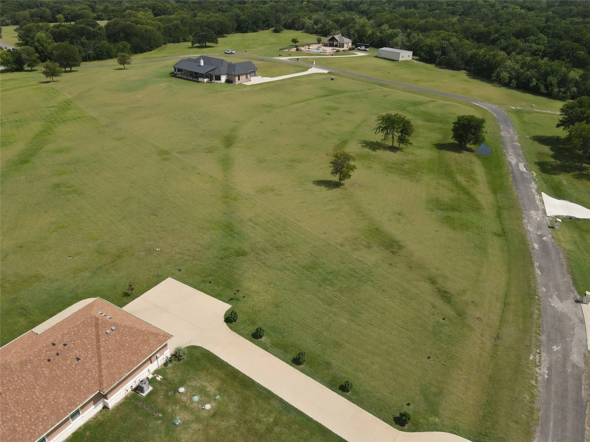 Expansive green landscape featuring multiple structures, a paved drive, and a private road