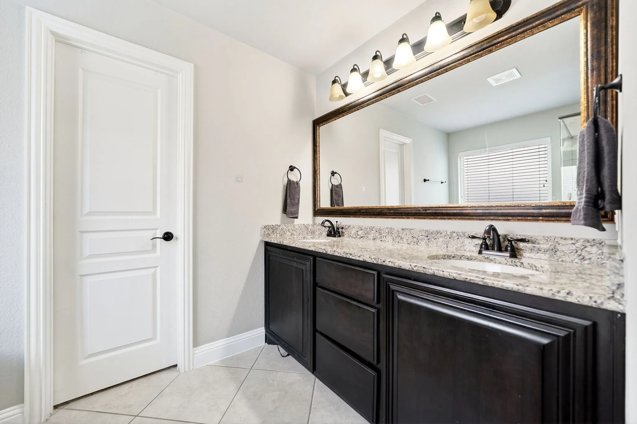 Double vanity featuring dark wood cabinetry, light-toned stone countertop, and two undermount sinks