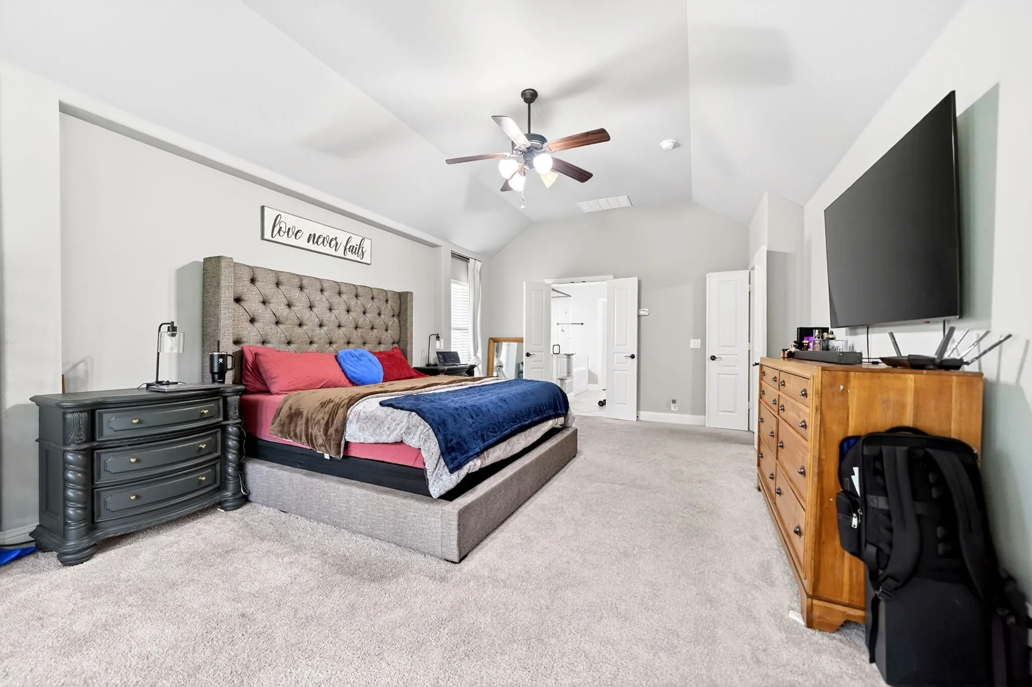 Spacious room featuring vaulted ceilings, light gray wall paint, and light-colored carpet flooring