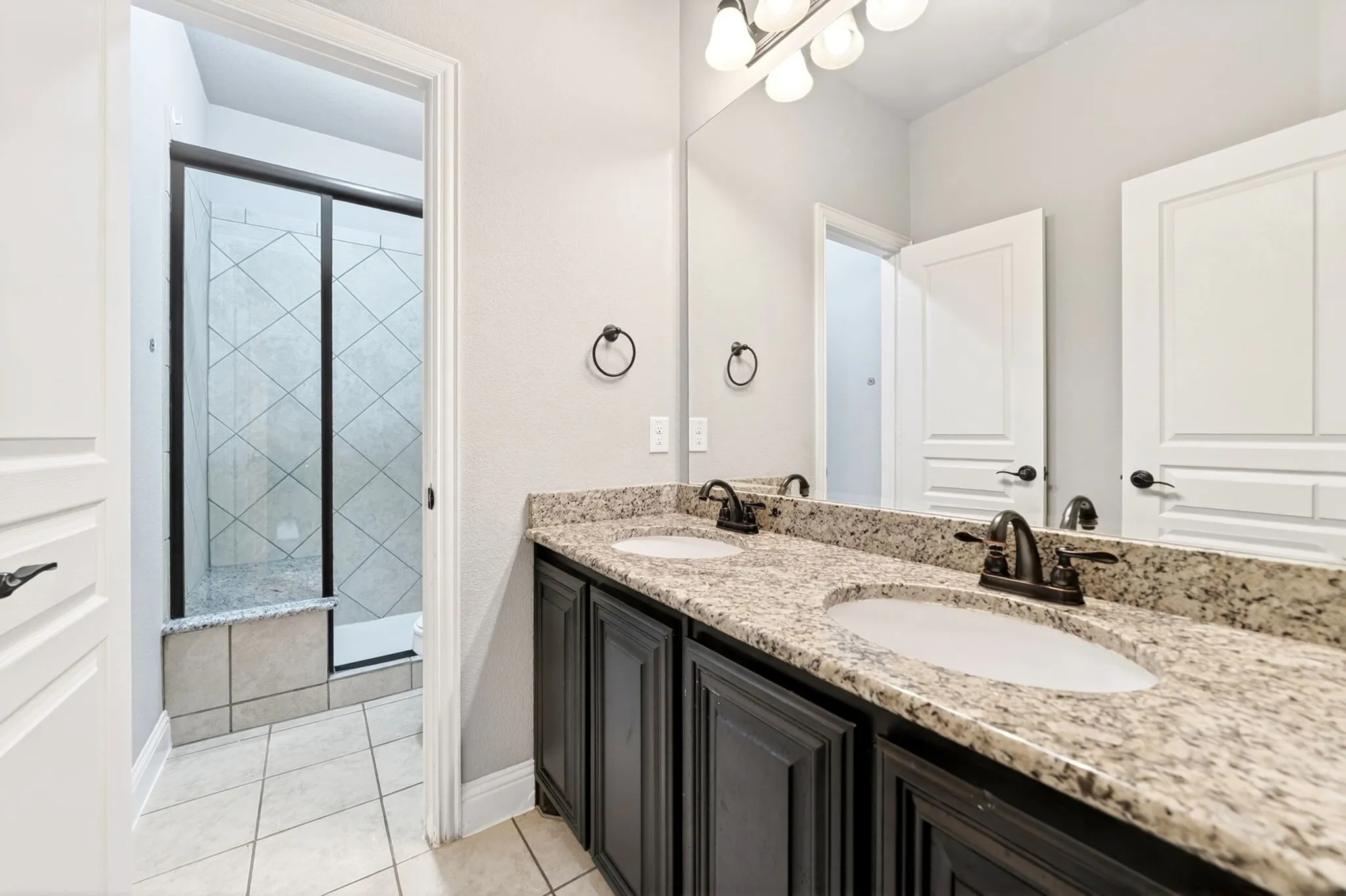 Bathroom featuring a dual vanity with granite countertops, undermount sinks, and oil-rubbed bronze fixtures