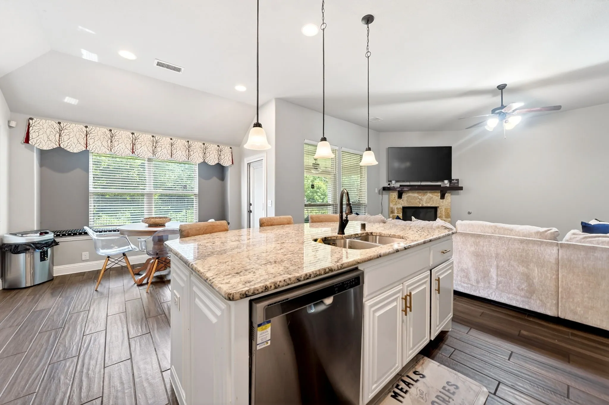 Kitchen island with granite countertop, stainless steel sink, and pendant lighting