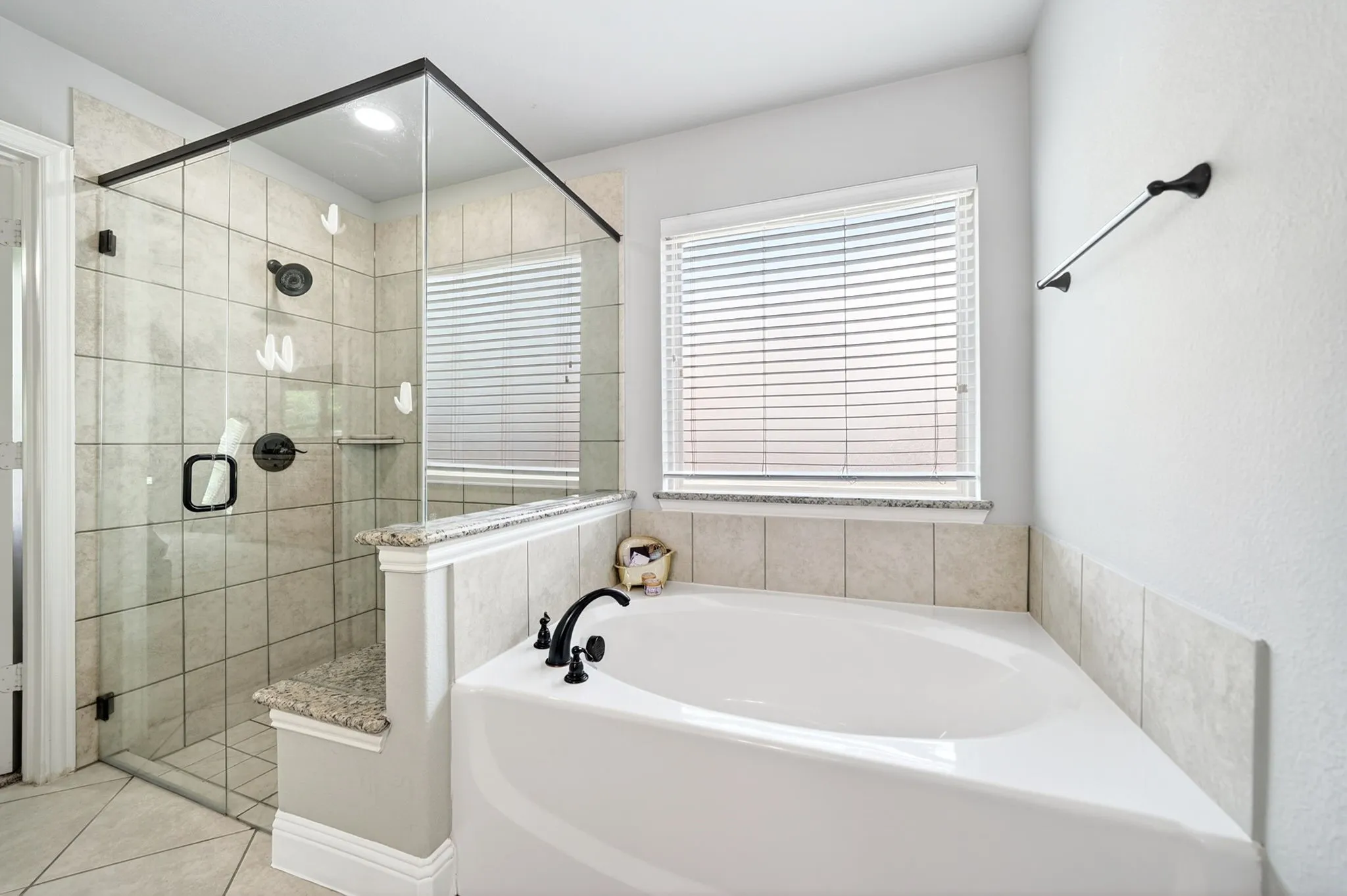 White soaking tub with black faucet hardware and a tiled surround