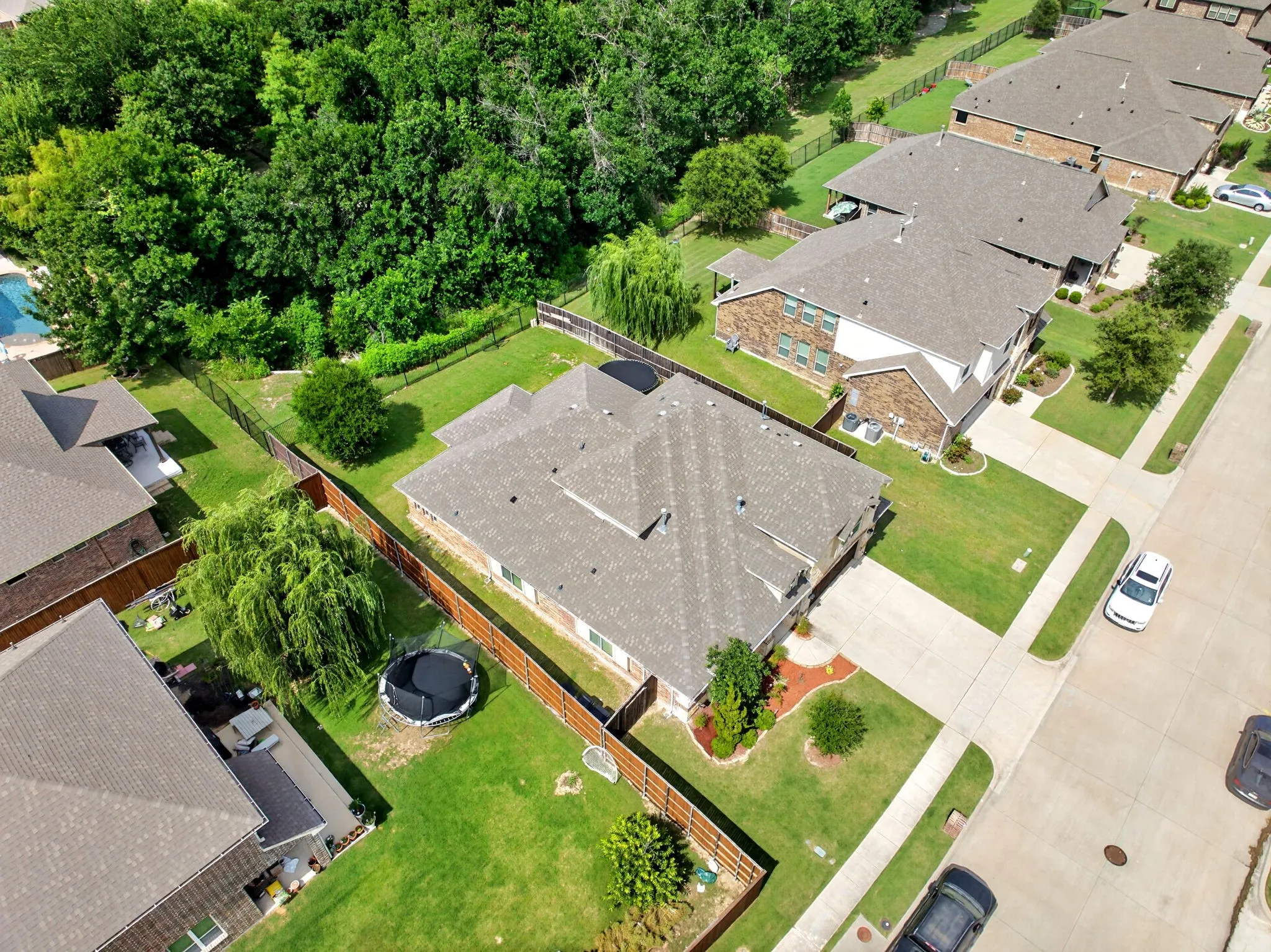 Aerial perspective showcasing a single-family residence with a substantial backyard, bordered by mature trees