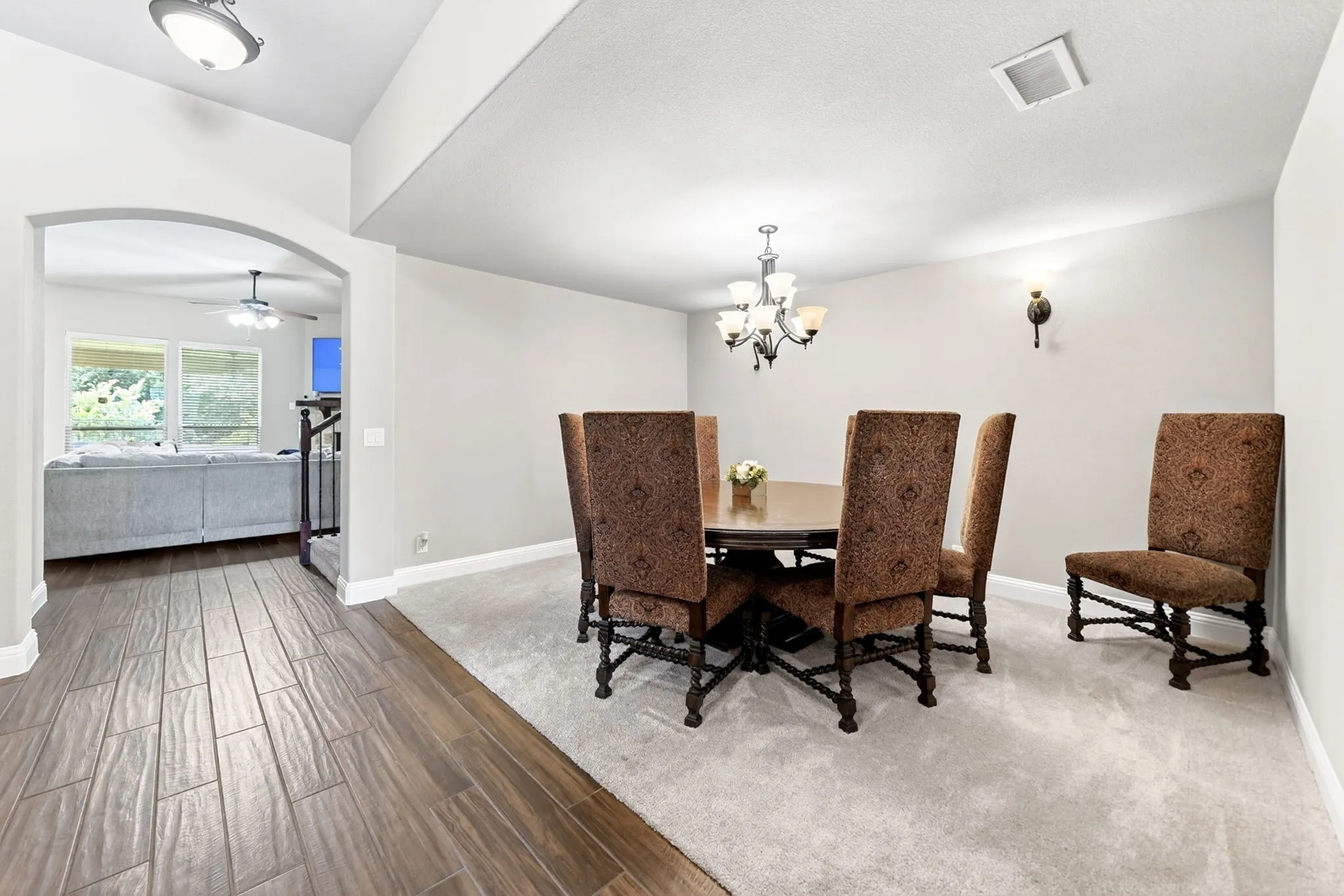Dining area featuring a chandelier and wall sconce, with carpeting and a hardwood-finish flooring entry