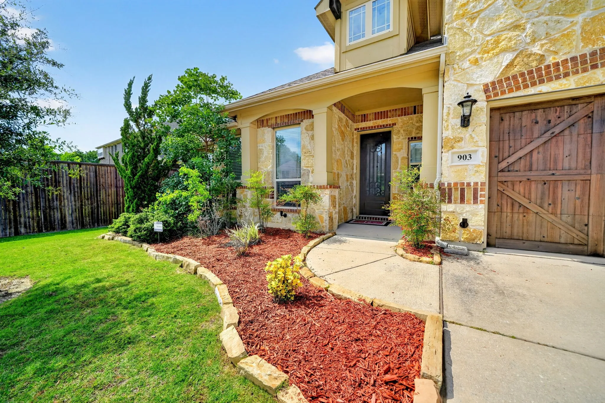 Stone and brick veneer exterior featuring a decorative wooden garage door
