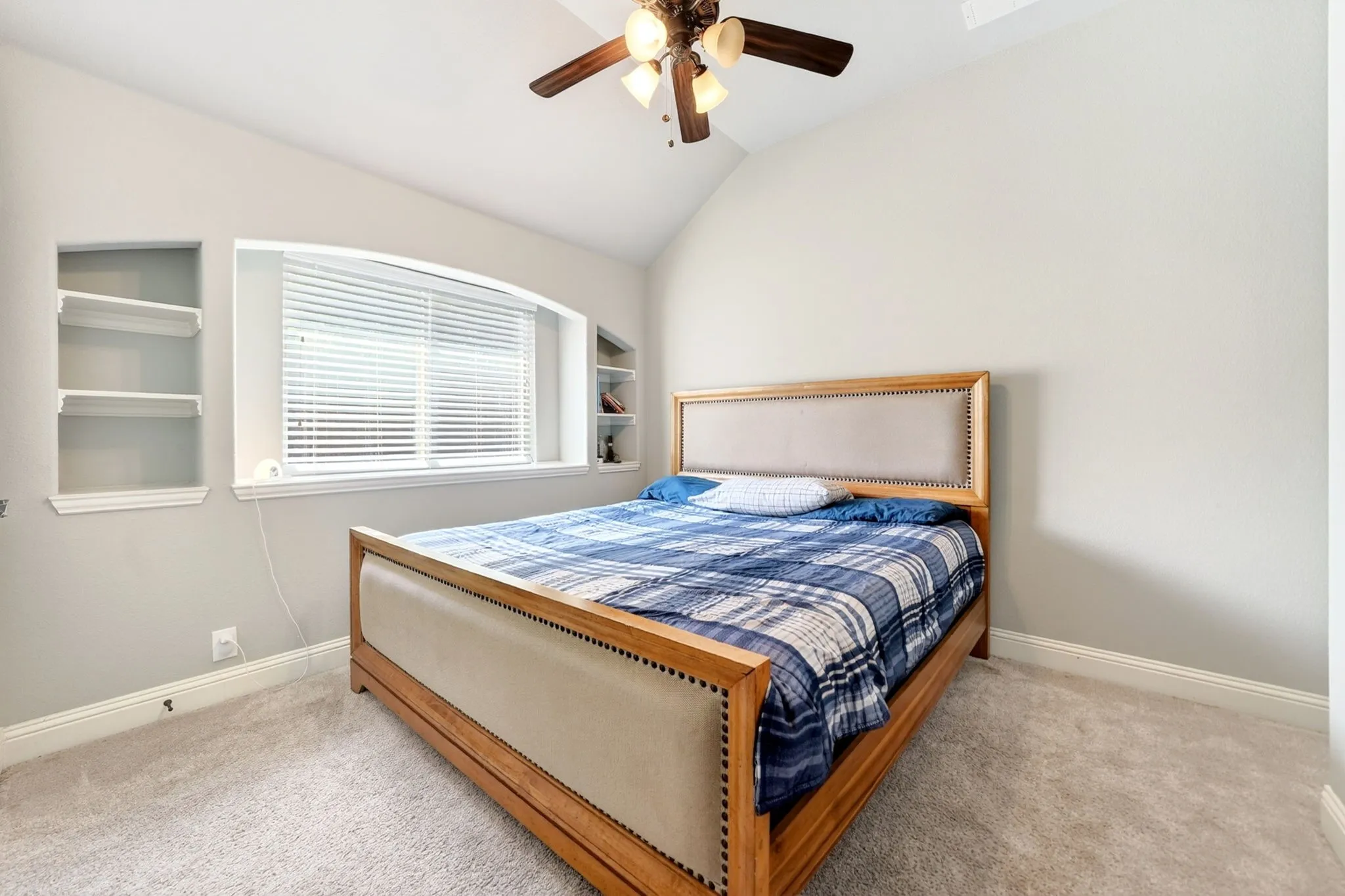 Recessed window with built-in shelving, vaulted ceiling, ceiling fan with integrated lighting, and neutral carpeting