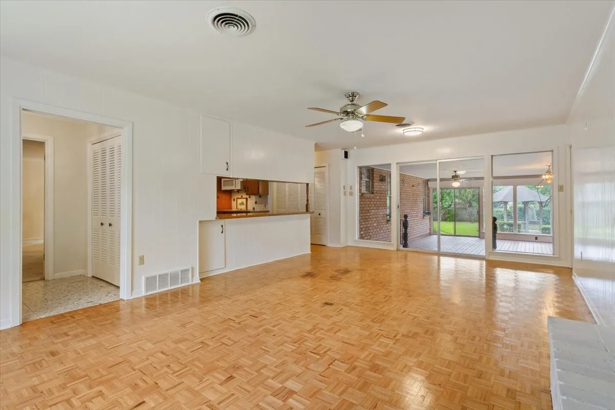 Living area with parquet flooring with entry to kitchen and sunroom