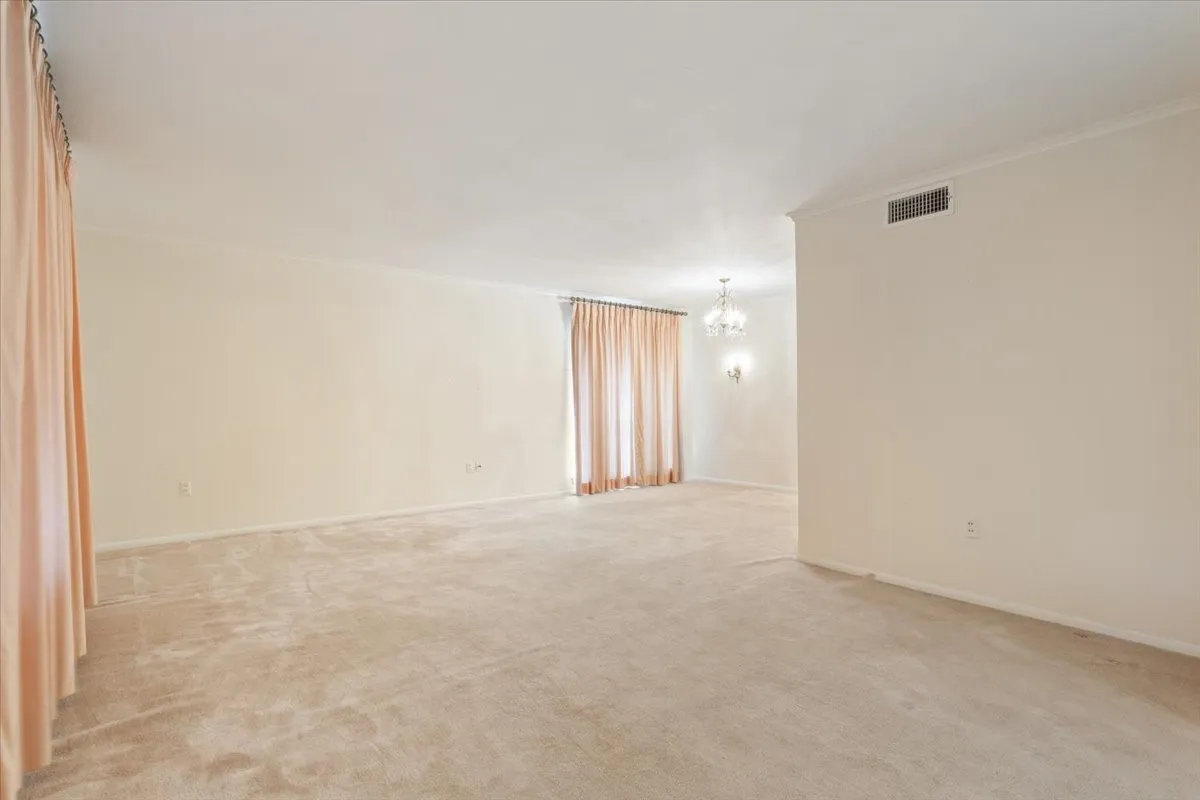 Large living and dining area with natural light and original chandeliers and wall sconces