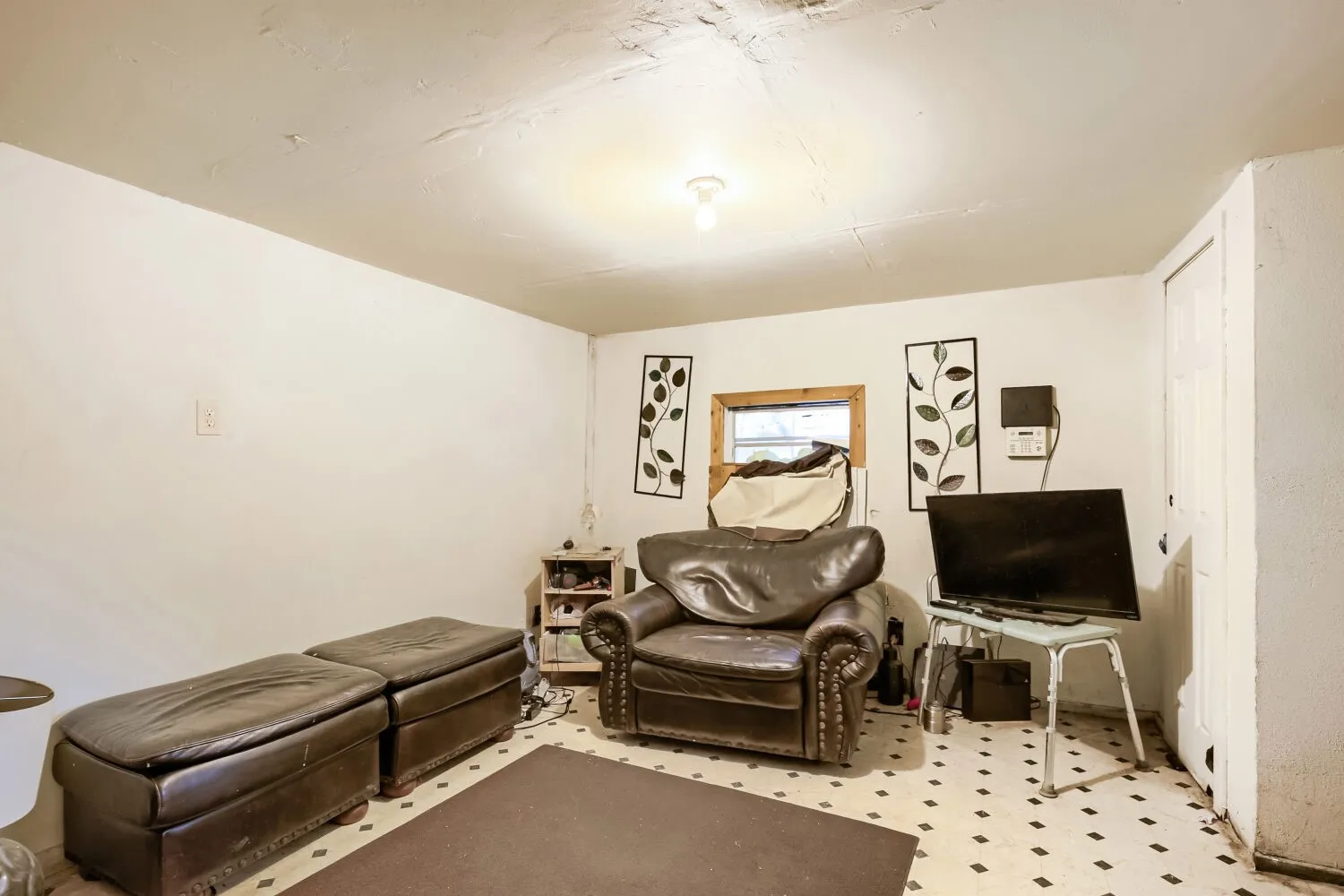Room featuring white walls, a single window with wood trim, and a built-in white door