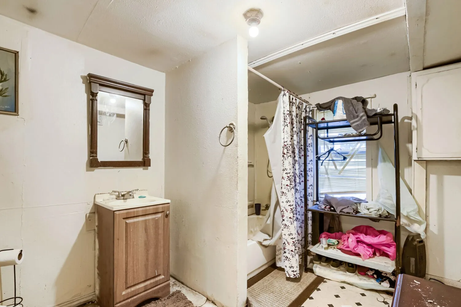 Bathroom featuring a single vanity with wood-finish cabinetry, a framed mirror, and a shower-over-tub combination