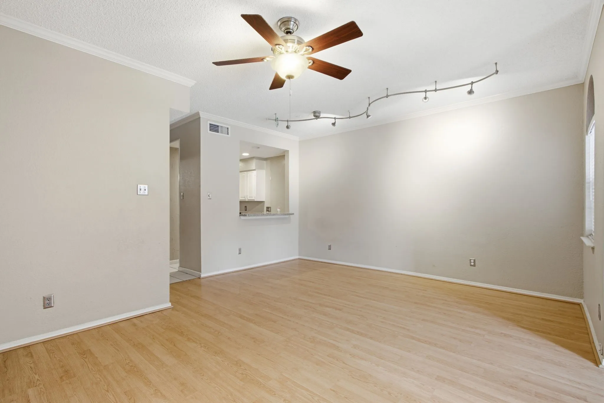 Open-concept living area featuring wood-finish flooring, crown molding, a ceiling fan with light fixture, and recessed track​​‌​​​​‌​​‌‌​‌‌​​​‌‌​‌​‌​‌​​​‌​​ lighting