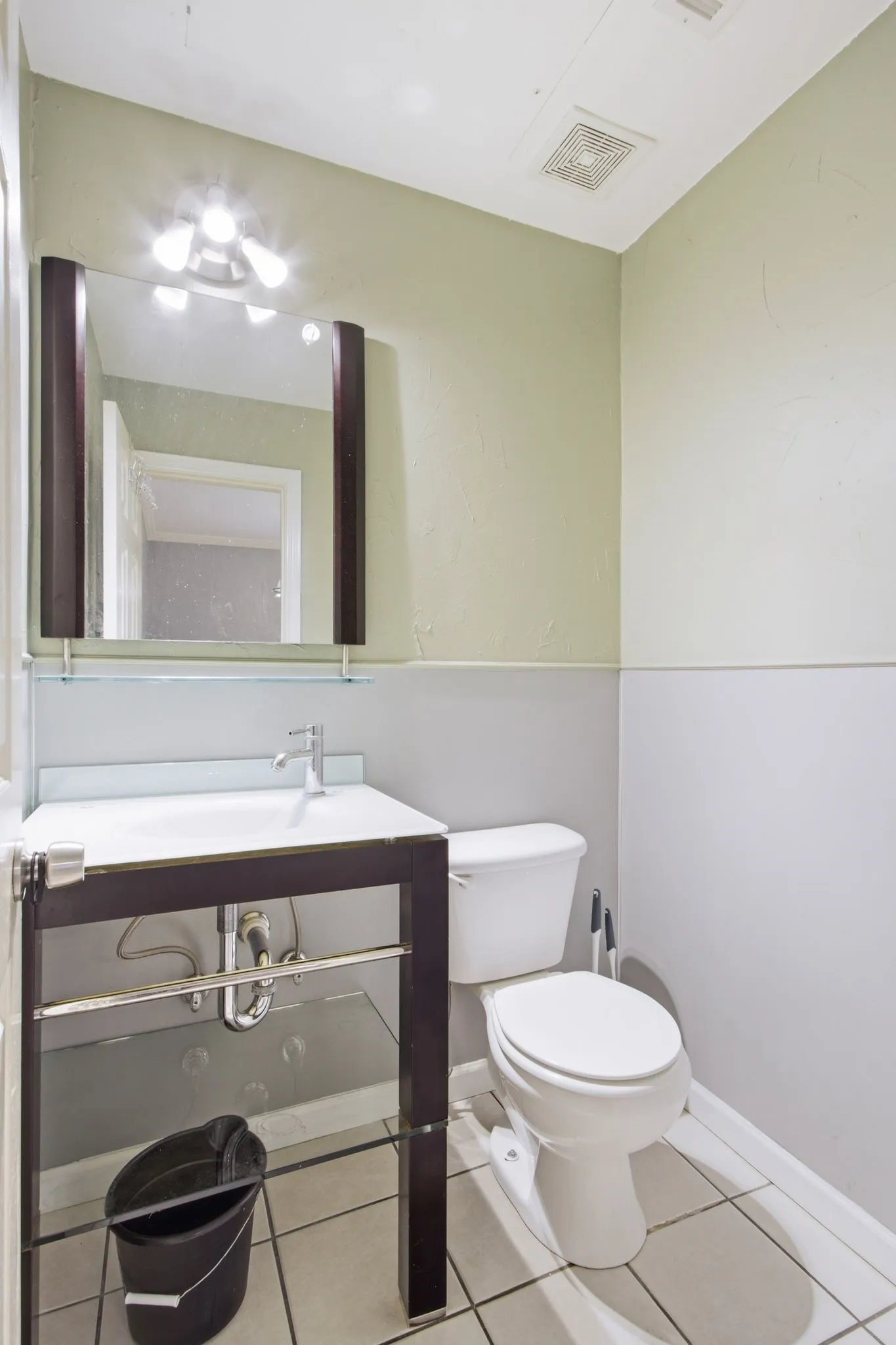Powder room featuring a modern vanity with a white countertop and basin, chrome faucet, and a wall-mounted mirror with integrated lighting