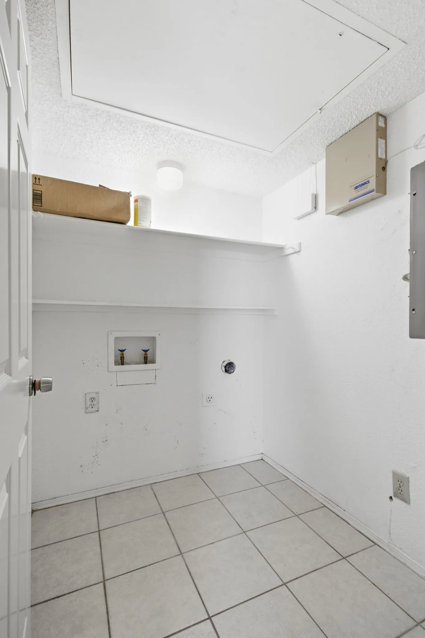 Utility room featuring tile flooring, built-in shelving, overhead lighting, and laundry hookups