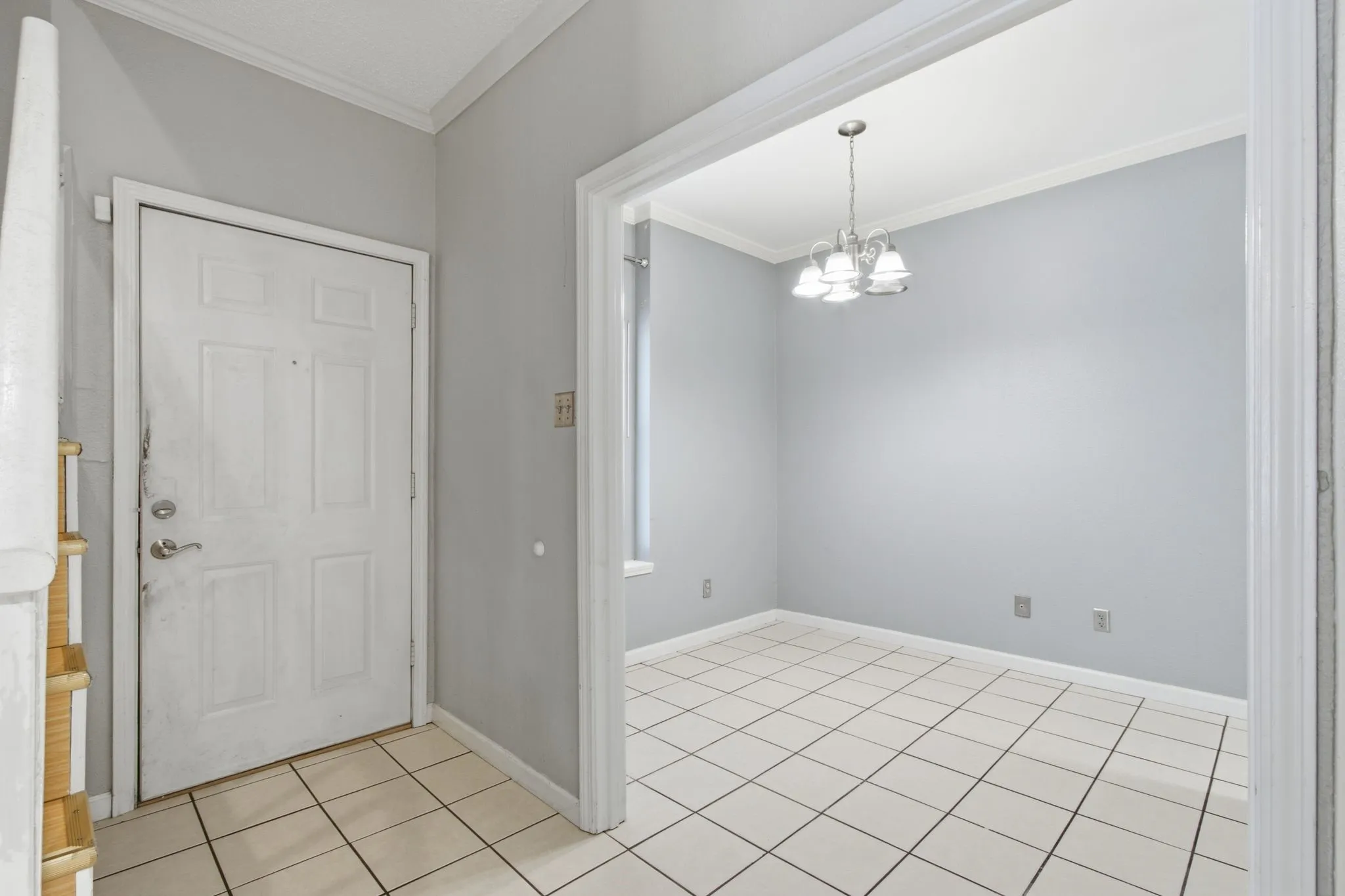 Entryway featuring light-colored tile flooring, a paneled door, and a staircase with wood-finish treads