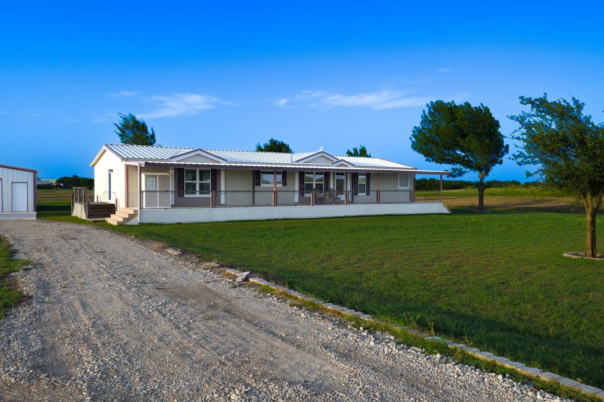Single-story residence featuring a covered front porch with railings, a metal roof, and light-colored siding