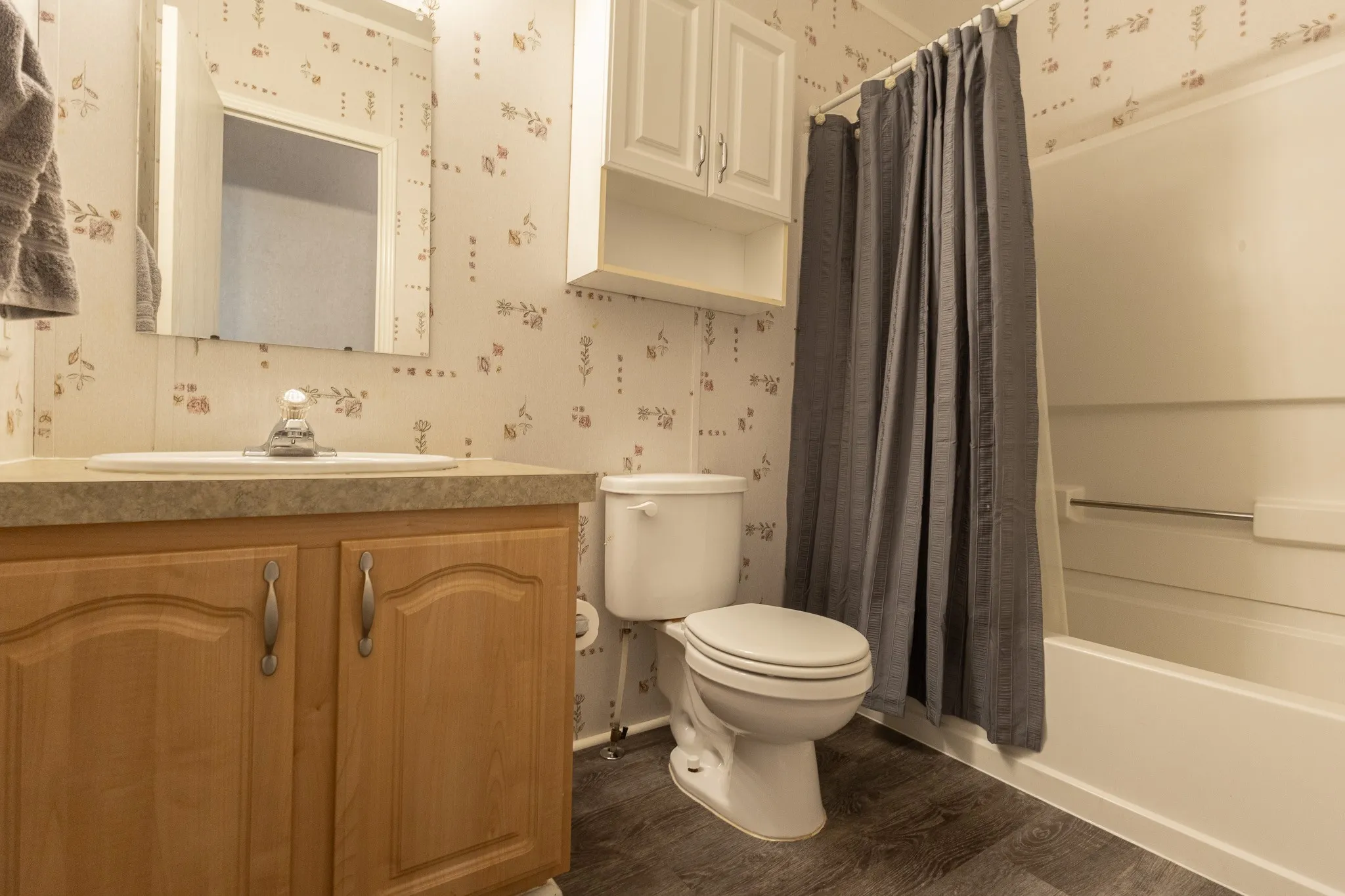 Bathroom with wood-finish vanity, integrated sink, and laminate countertop
