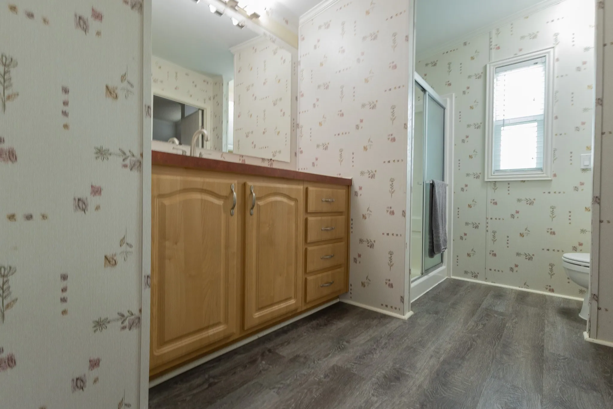 Bathroom featuring a wood-finish vanity with a reddish countertop, an integrated sink, and a mirrored medicine cabinet