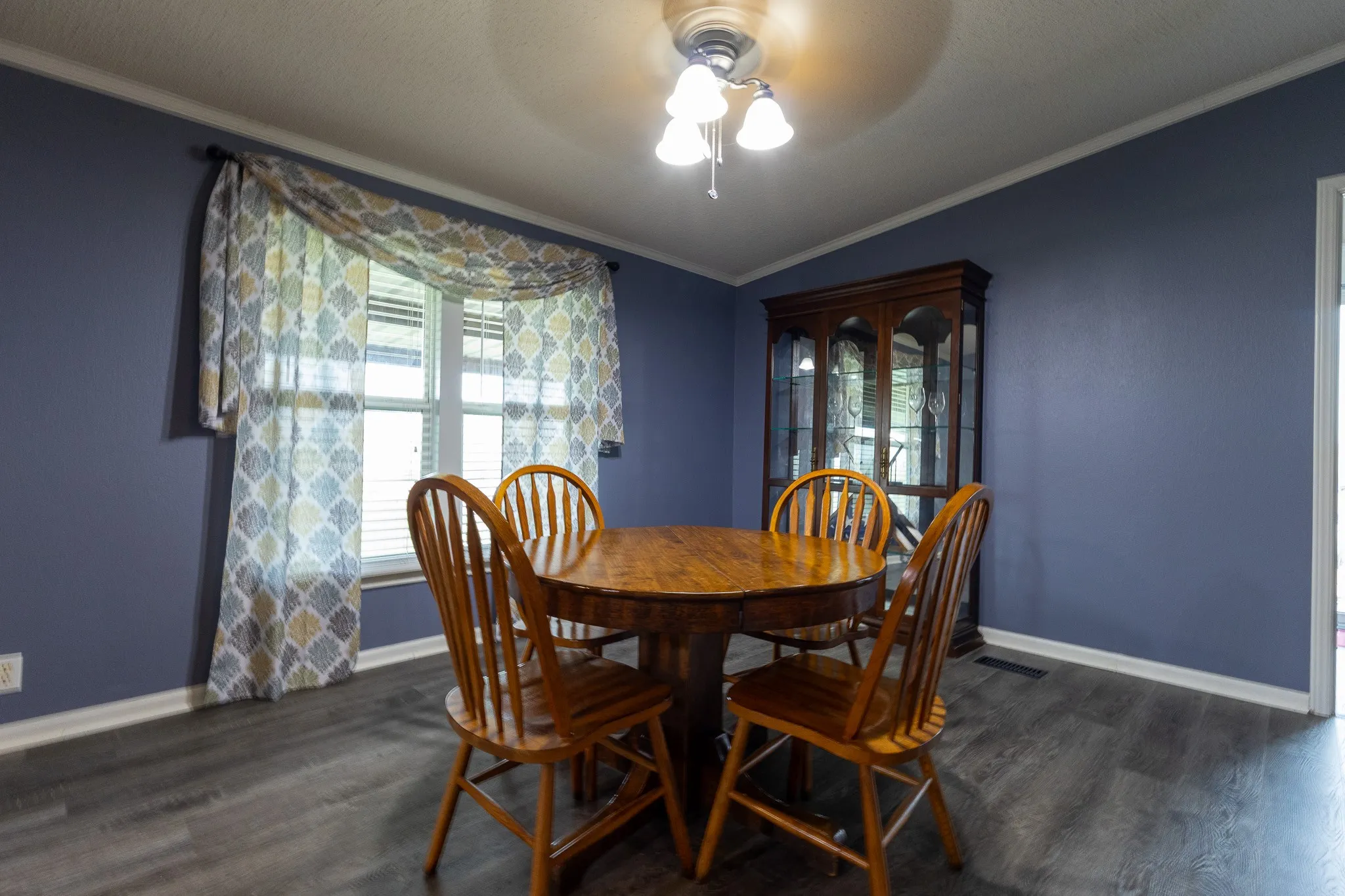 Dining area featuring wood-finish flooring, a double window with blinds, and crown molding