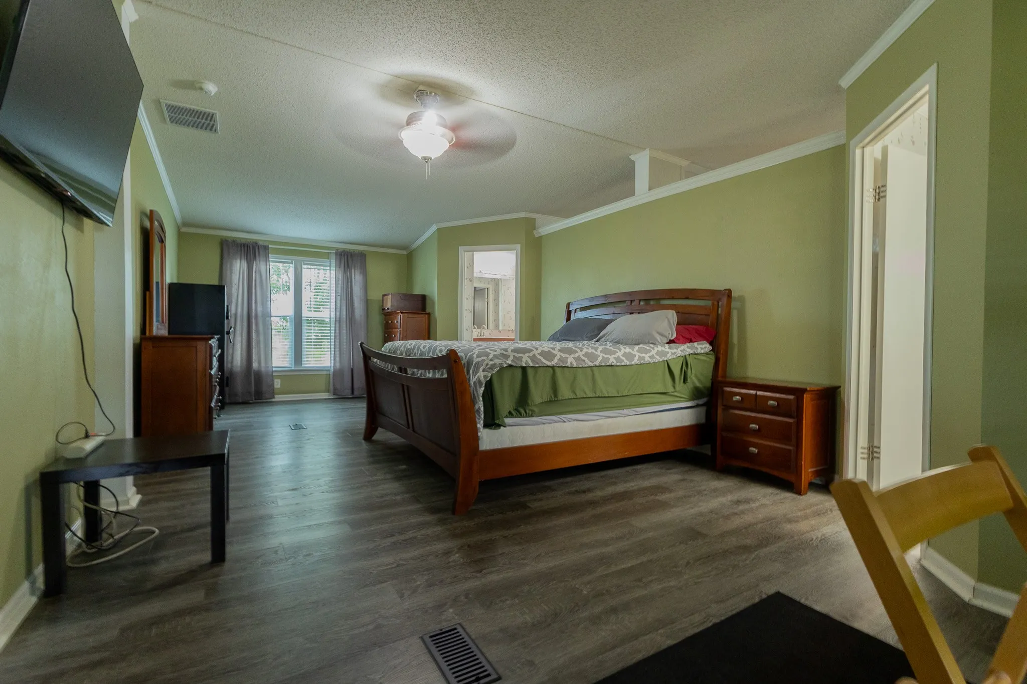Spacious room featuring wood-finish flooring, light green walls, and ample natural light from multiple windows