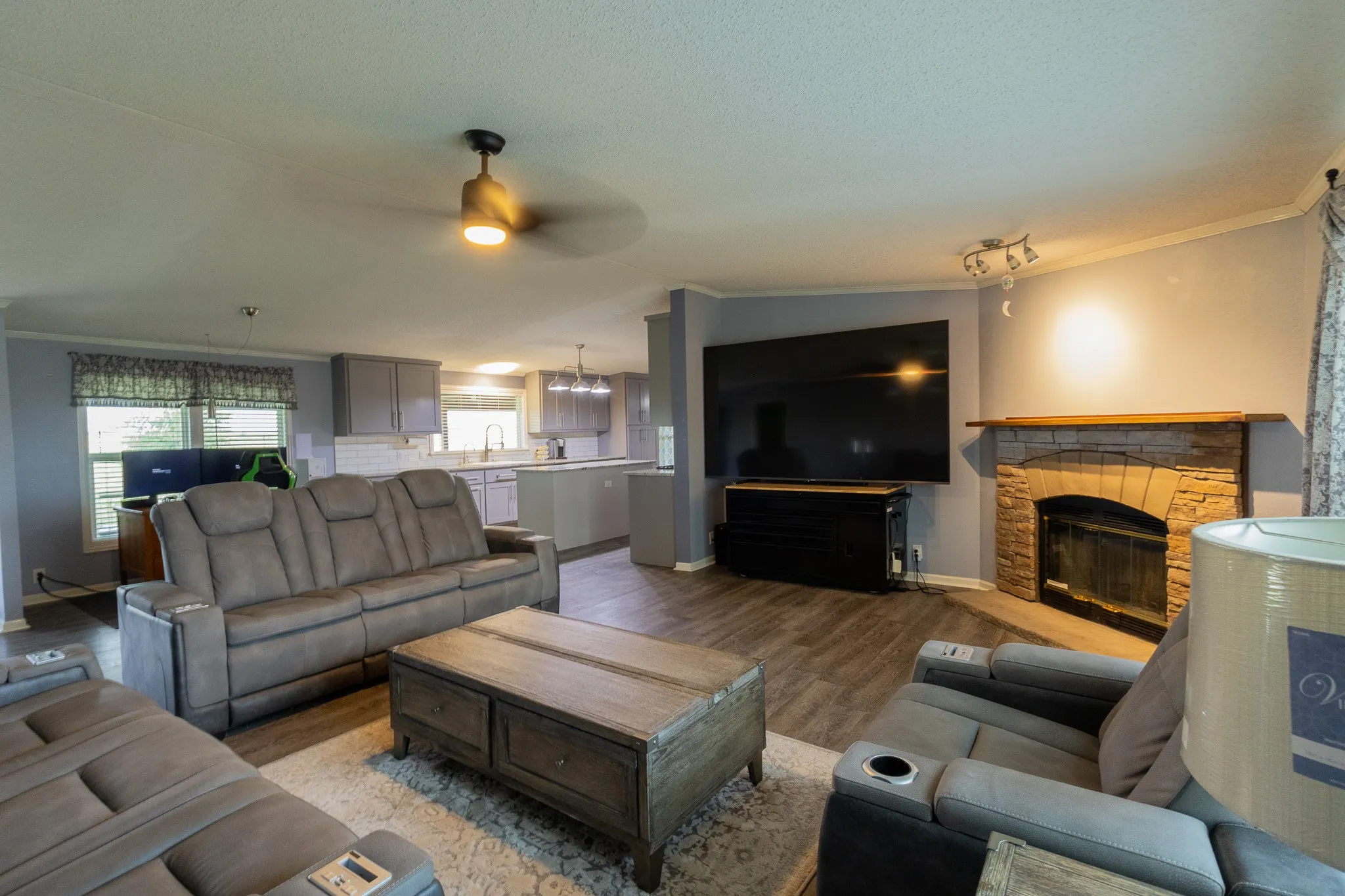 Open concept living area featuring wood-finish flooring and a stone-clad fireplace