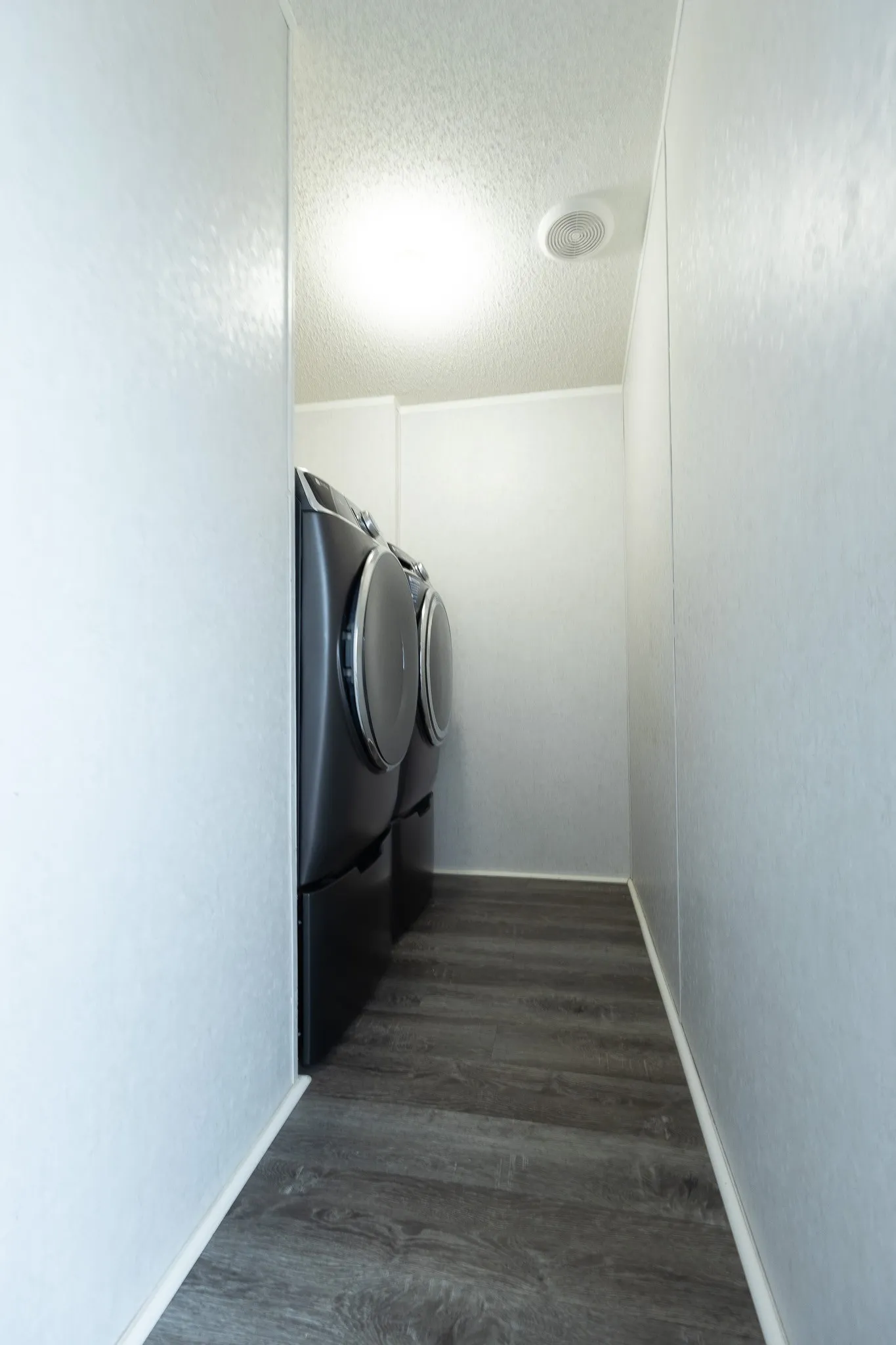Dedicated laundry area featuring wood-finish flooring, a ceiling-mounted light fixture, and a white ceiling with a textured finish