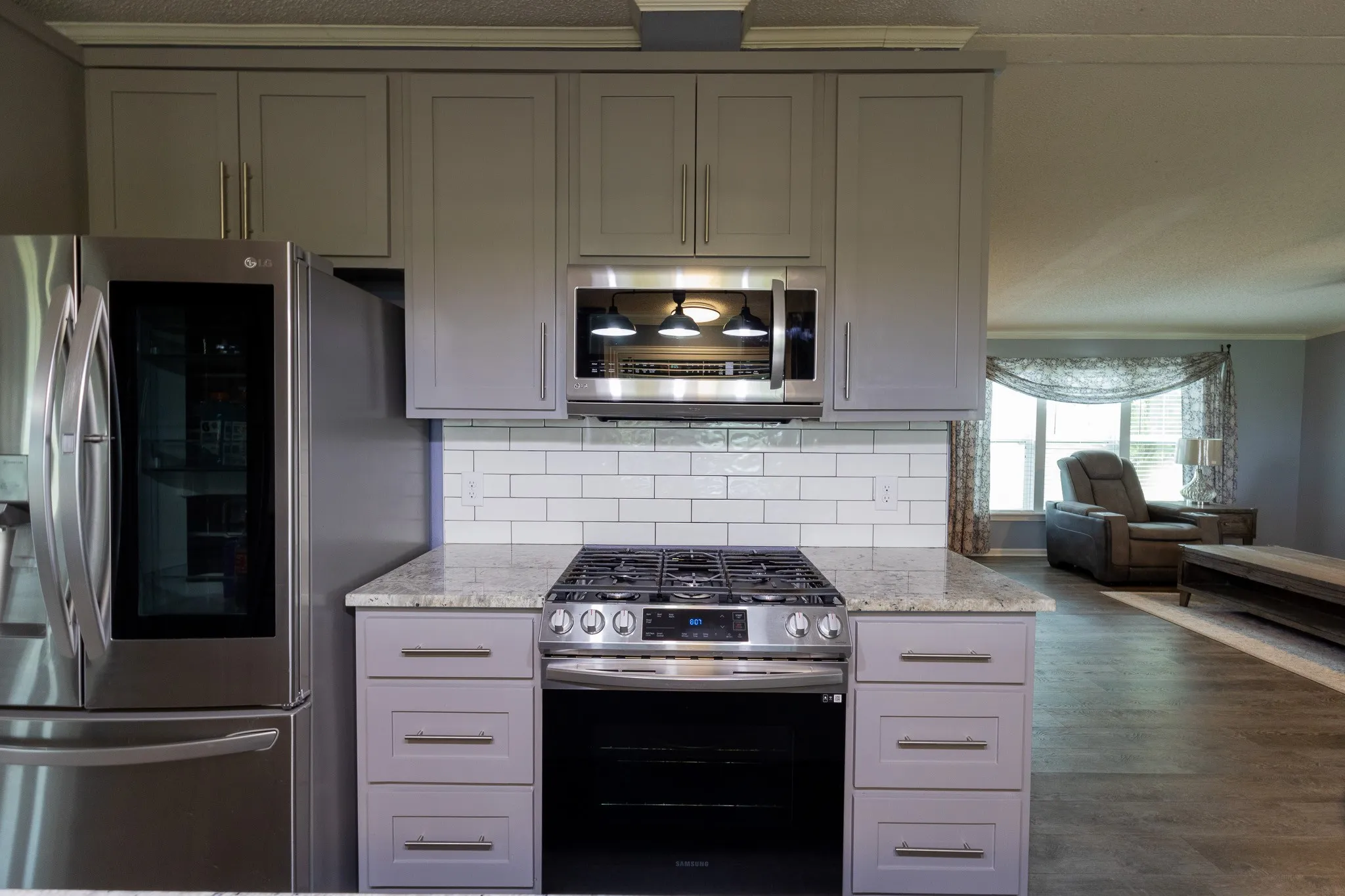 Kitchen featuring stainless steel appliances, light gray shaker cabinetry, a gas range with an overhead microwave, and a subway tile backsplash