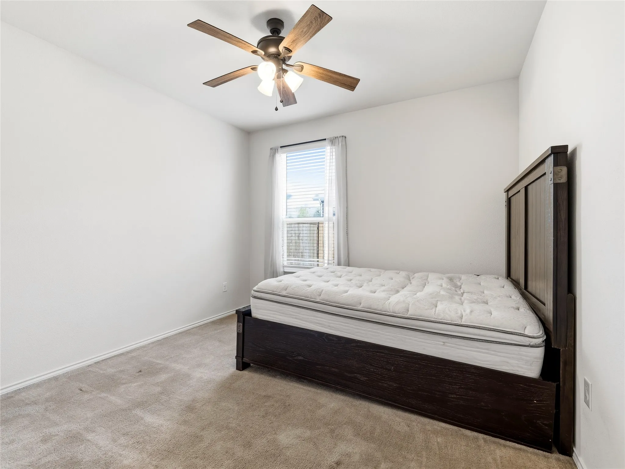 Carpeted room with a ceiling fan featuring integrated lighting, a window with blinds, and white walls