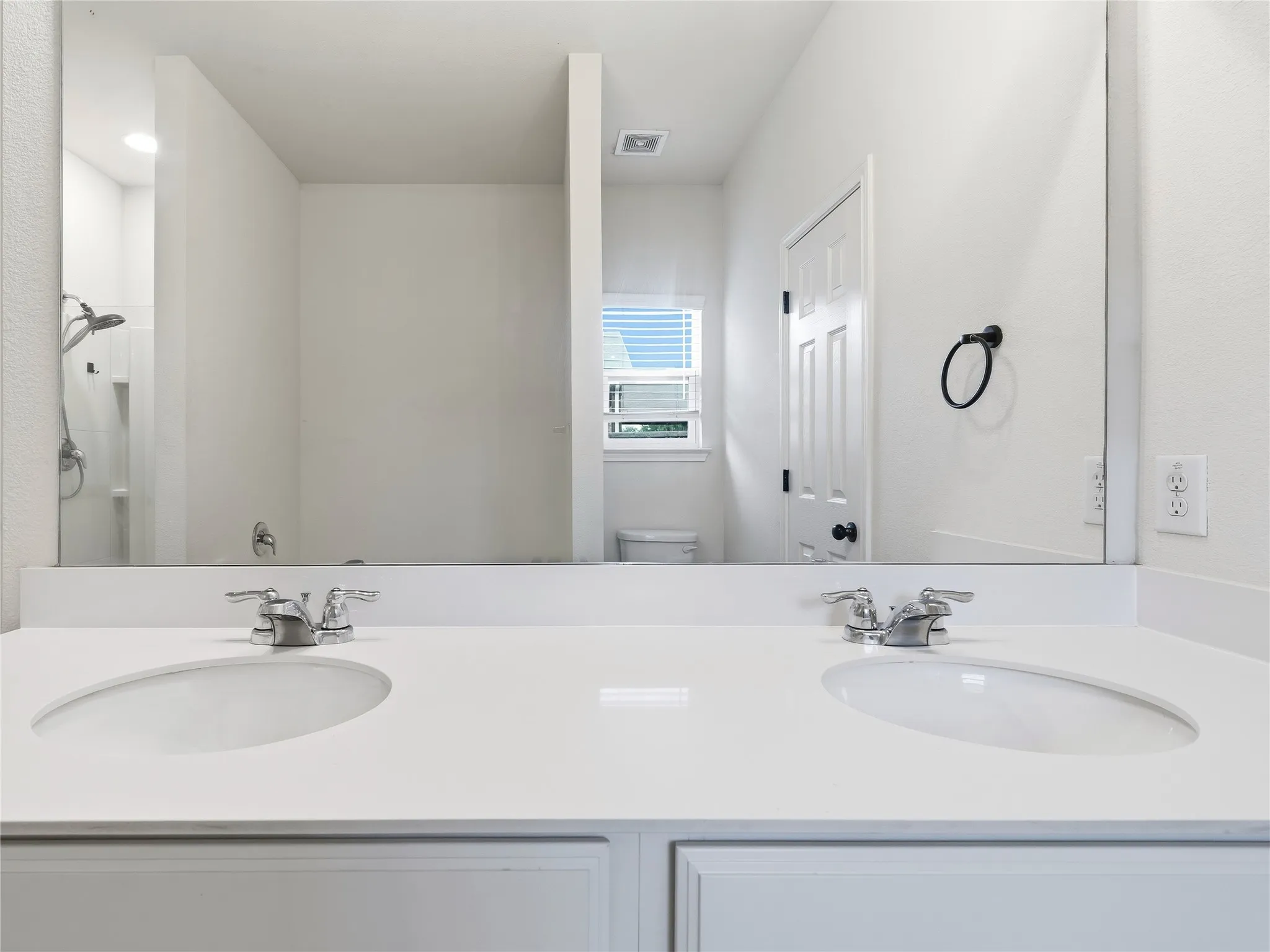Dual undermount sinks set into a white countertop with chrome fixtures