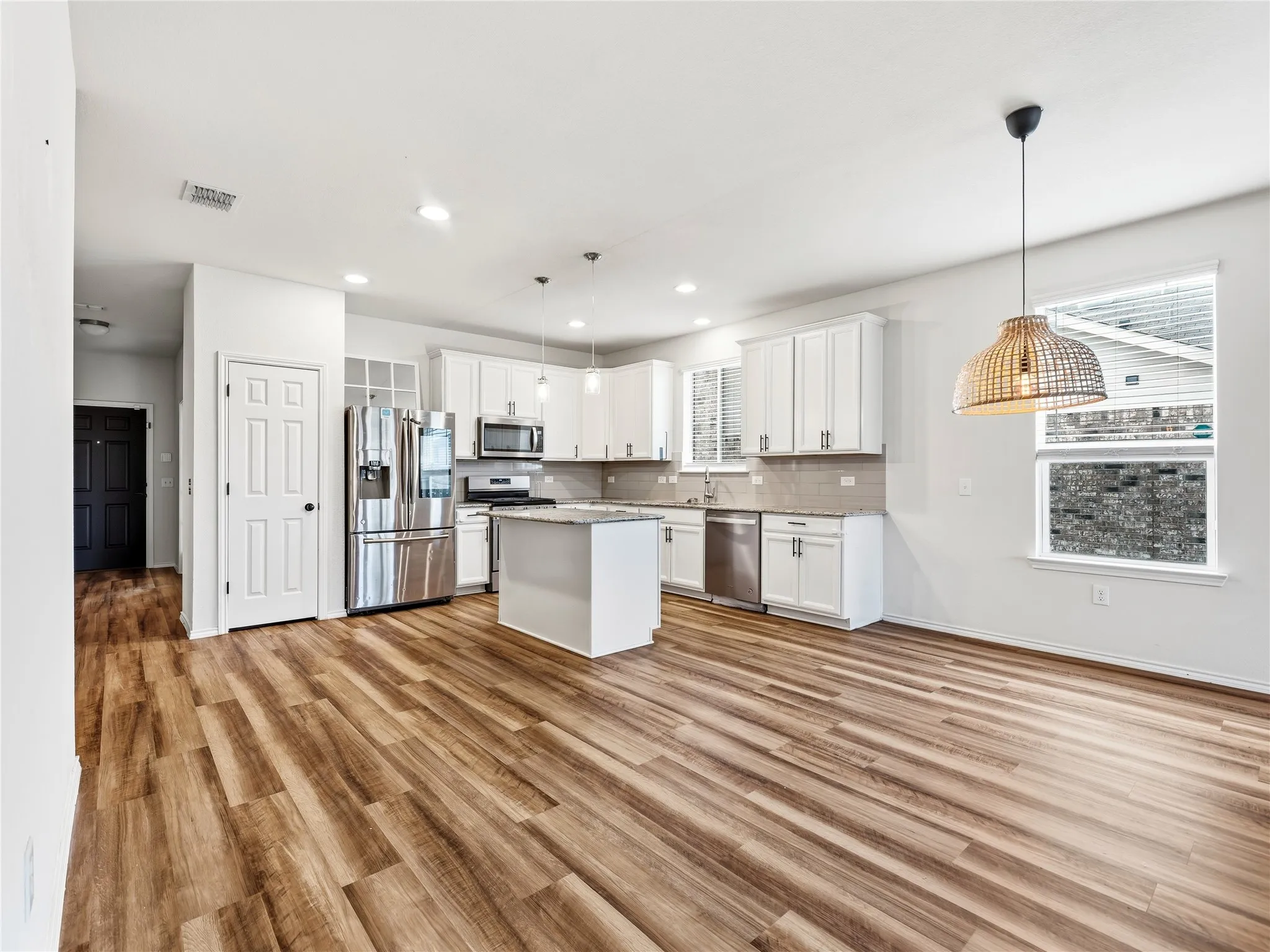 Contemporary kitchen featuring white cabinetry, stainless steel appliances, a center island with countertop, and wood-finish flooring